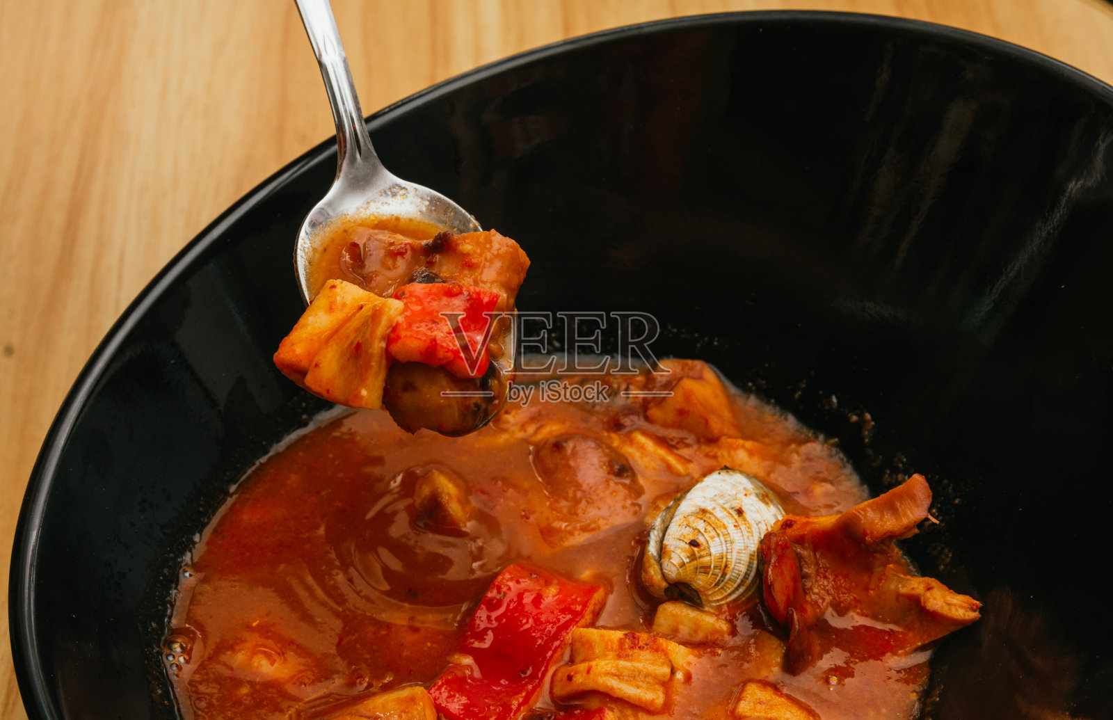 海鲜汤，有虾，牡蛎，章鱼，螃蟹，盛在深黑色的盘子里照片摄影图片