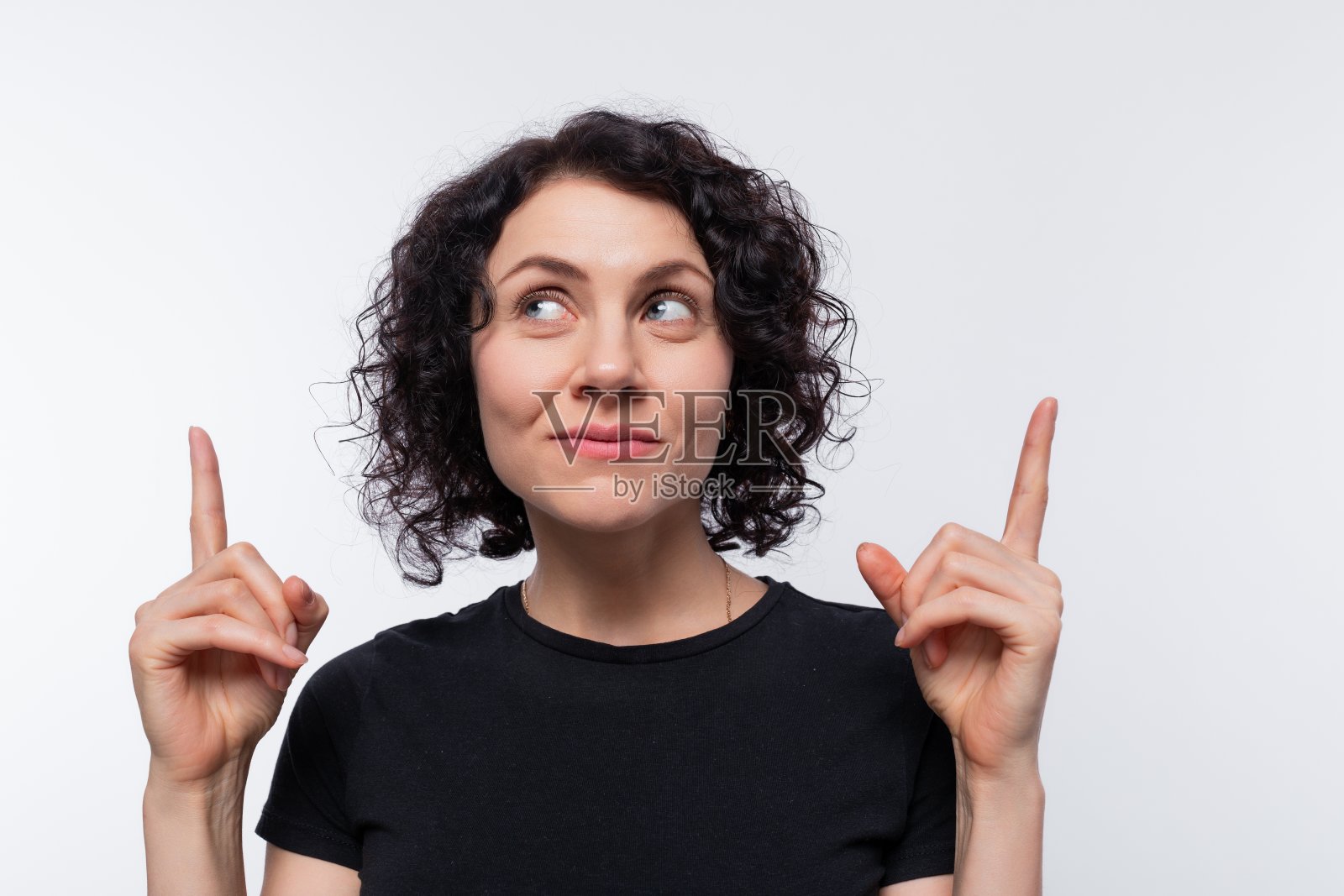 一头卷发的黑发美女穿着黑色t恤，手举食指照片摄影图片