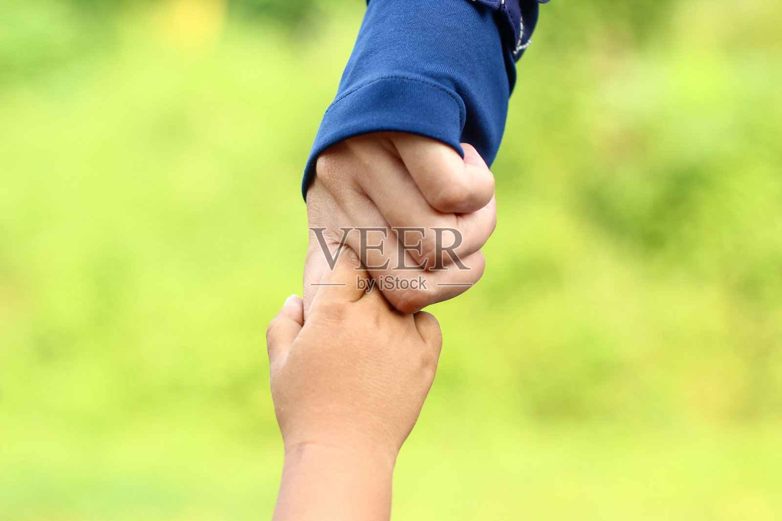 一个穆斯林母亲牵着她孩子的手的特写。家庭照片摄影图片