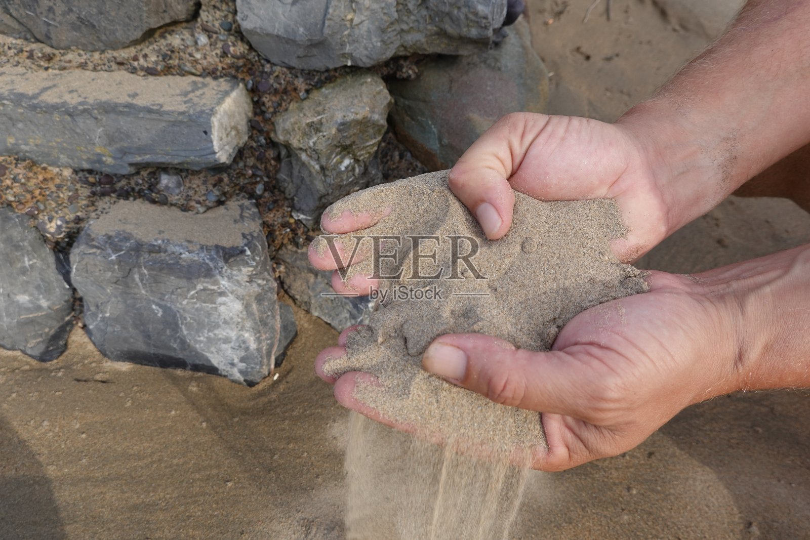 男人的手在沙滩上捡沙子。手里拿着沙滩照片摄影图片