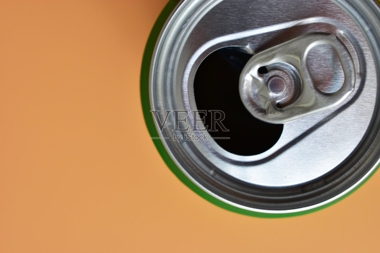 铝制绿色饮料罐，桔黄色底色，开冷鲜饮料照片摄影图片