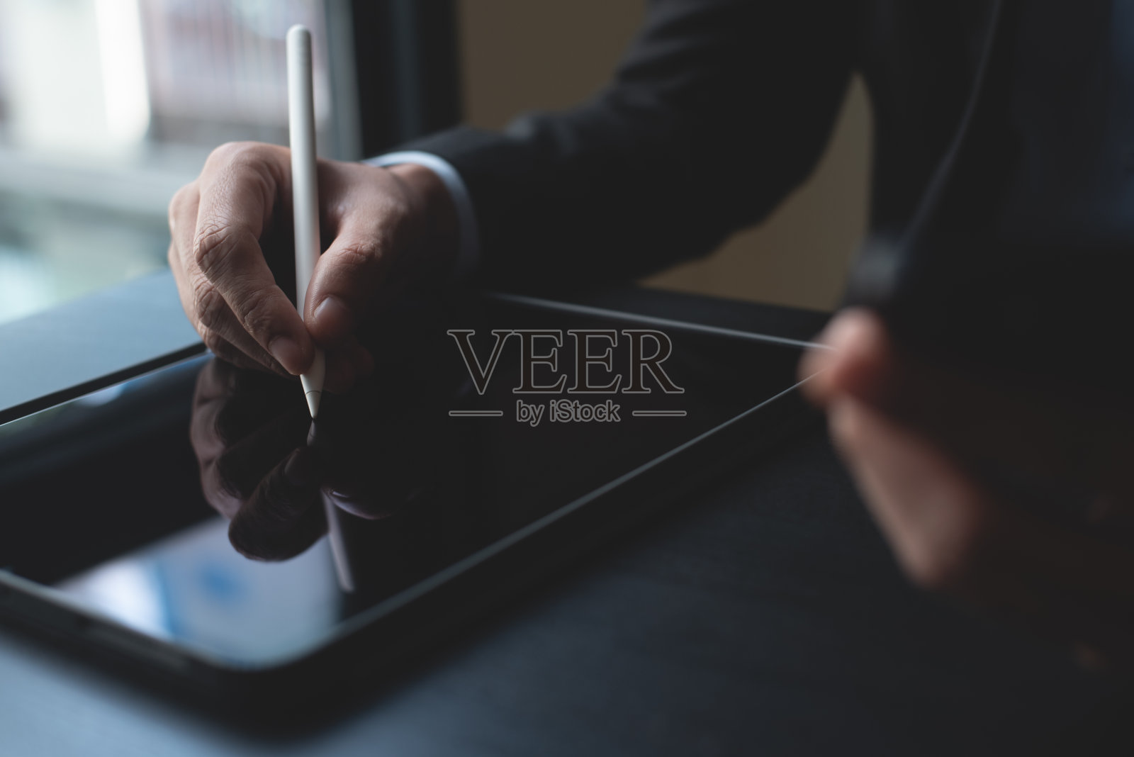 商人用触控笔在数码平板电脑上签署电子文件的特写。商务人士策划工作项目，办公桌上数码文件打样，电子签名，电子签名照片摄影图片