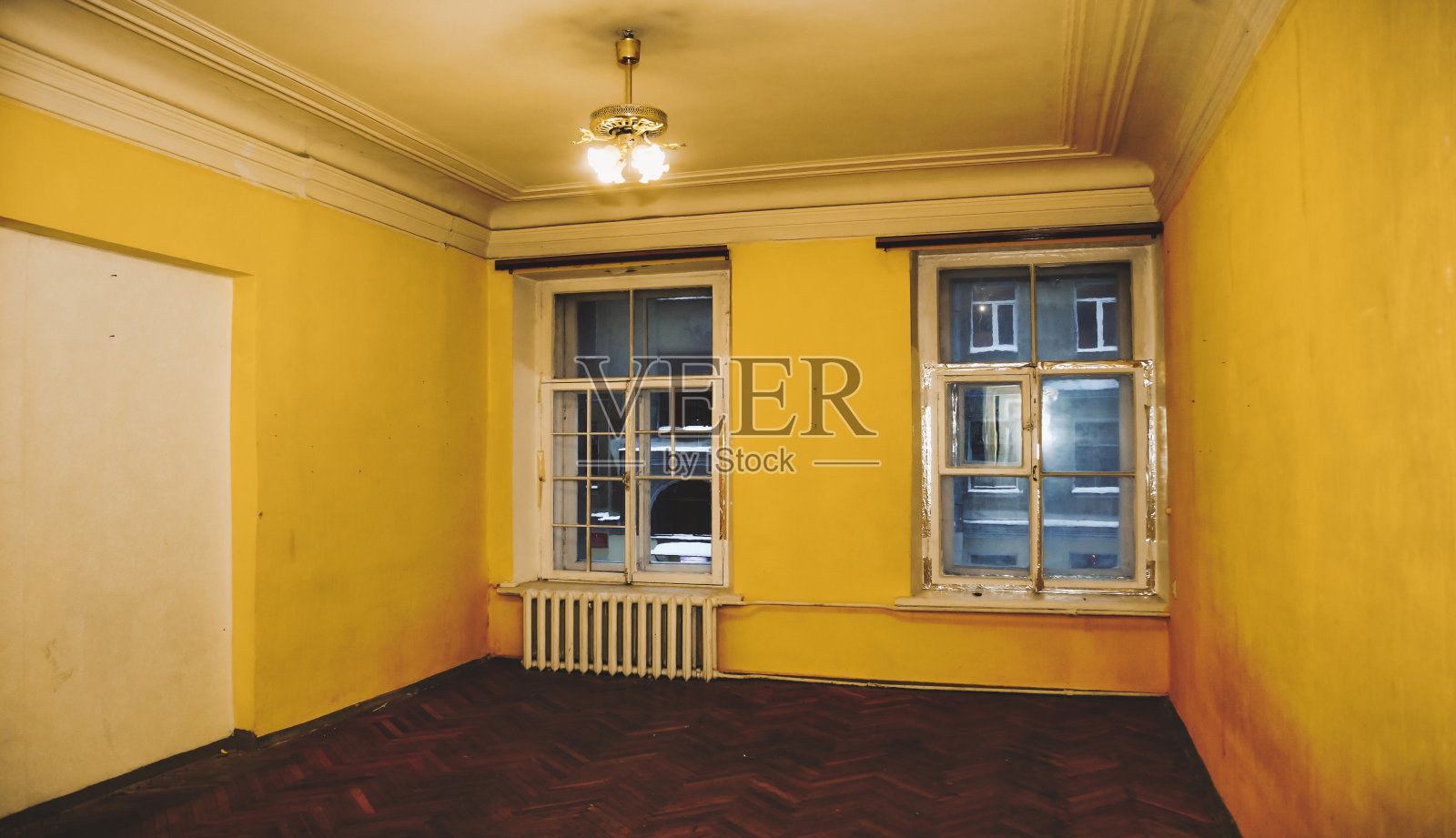 背景是一个废弃的公共公寓的黄色房间内部，肮脏腐烂剥落的墙壁。破旧的过去，皱巴巴的地板，皱巴巴的墙纸。装修理念。复制广告文本空间照片摄影图片