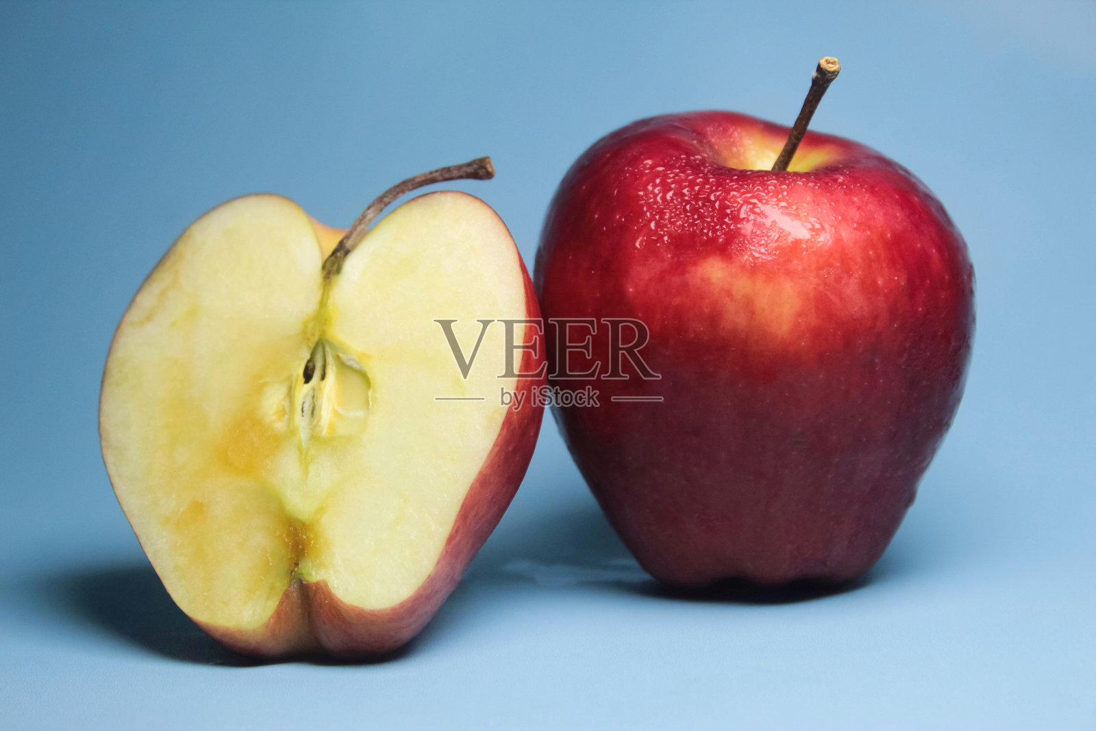 蓝色背景上的红苹果和半个苹果照片摄影图片