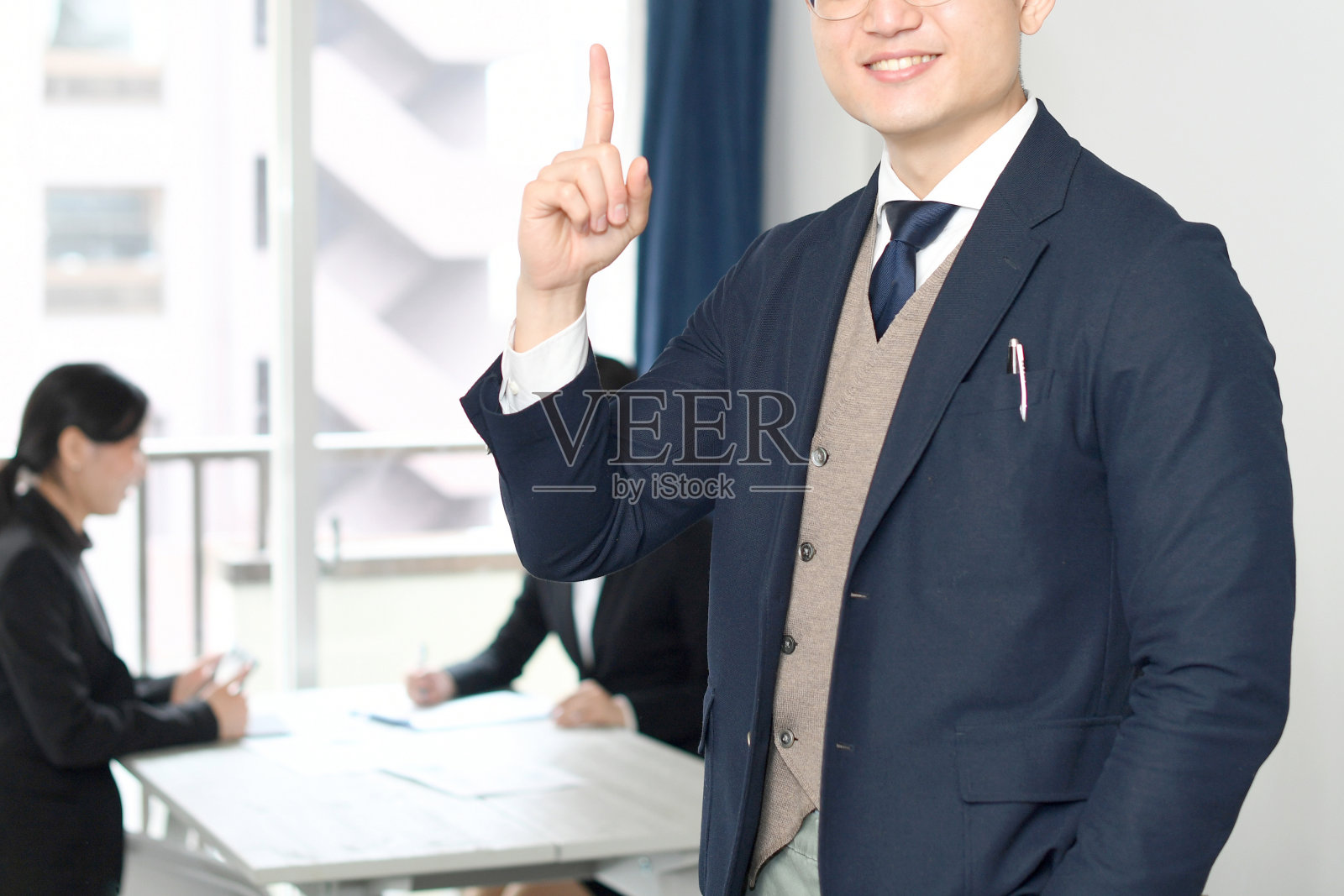 年轻的亚洲人穿着西装，在办公室里挥舞着食指照片摄影图片