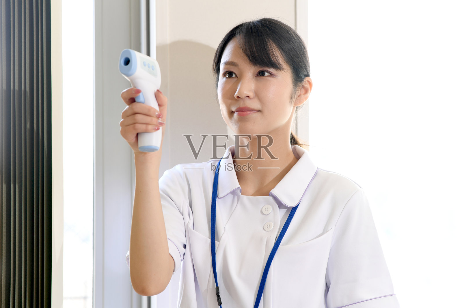 一名年轻的亚洲女医务工作者用辐射体温计测量体温照片摄影图片