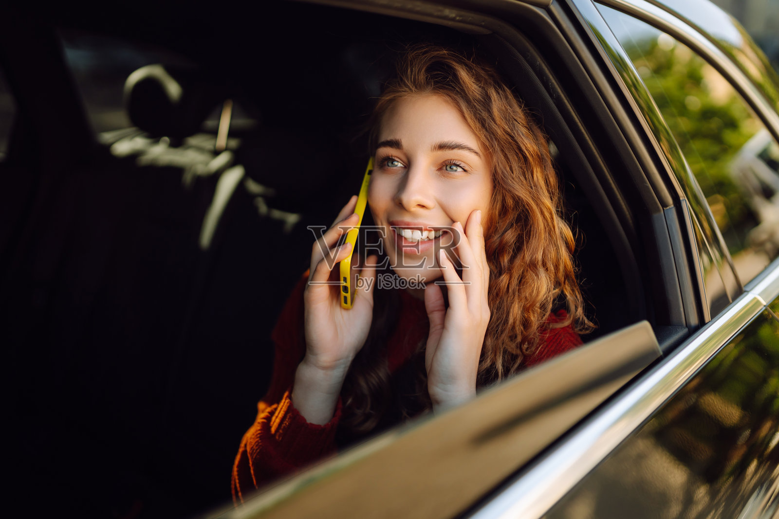 美女在汽车后座拿着手机。照片摄影图片