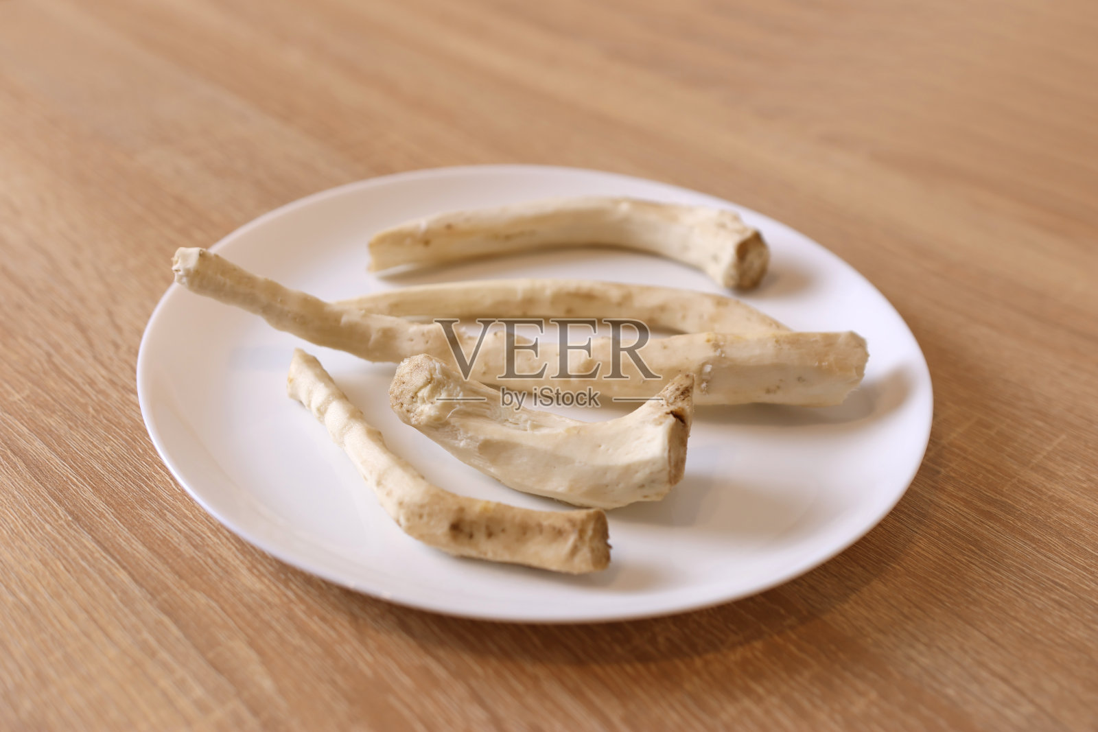去皮的辣根放在白色盘子里照片摄影图片