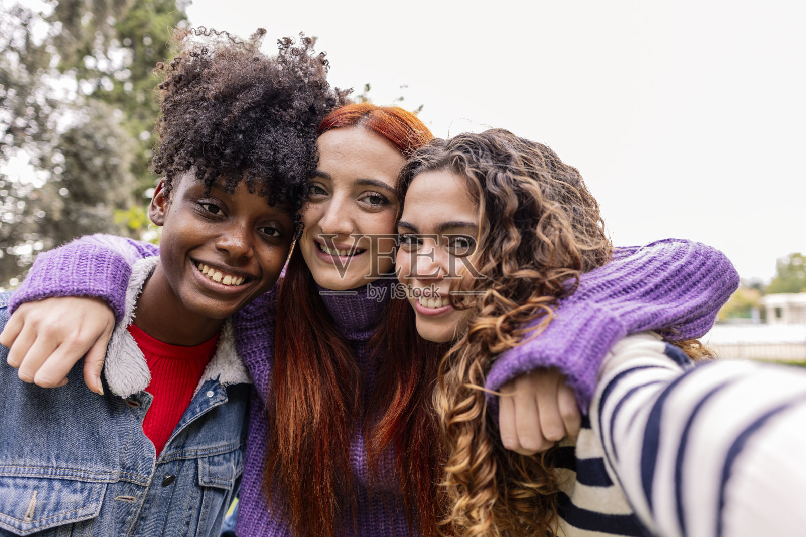三个女孩在自拍。一群年轻的多元文化女性看着相机拍照照片摄影图片