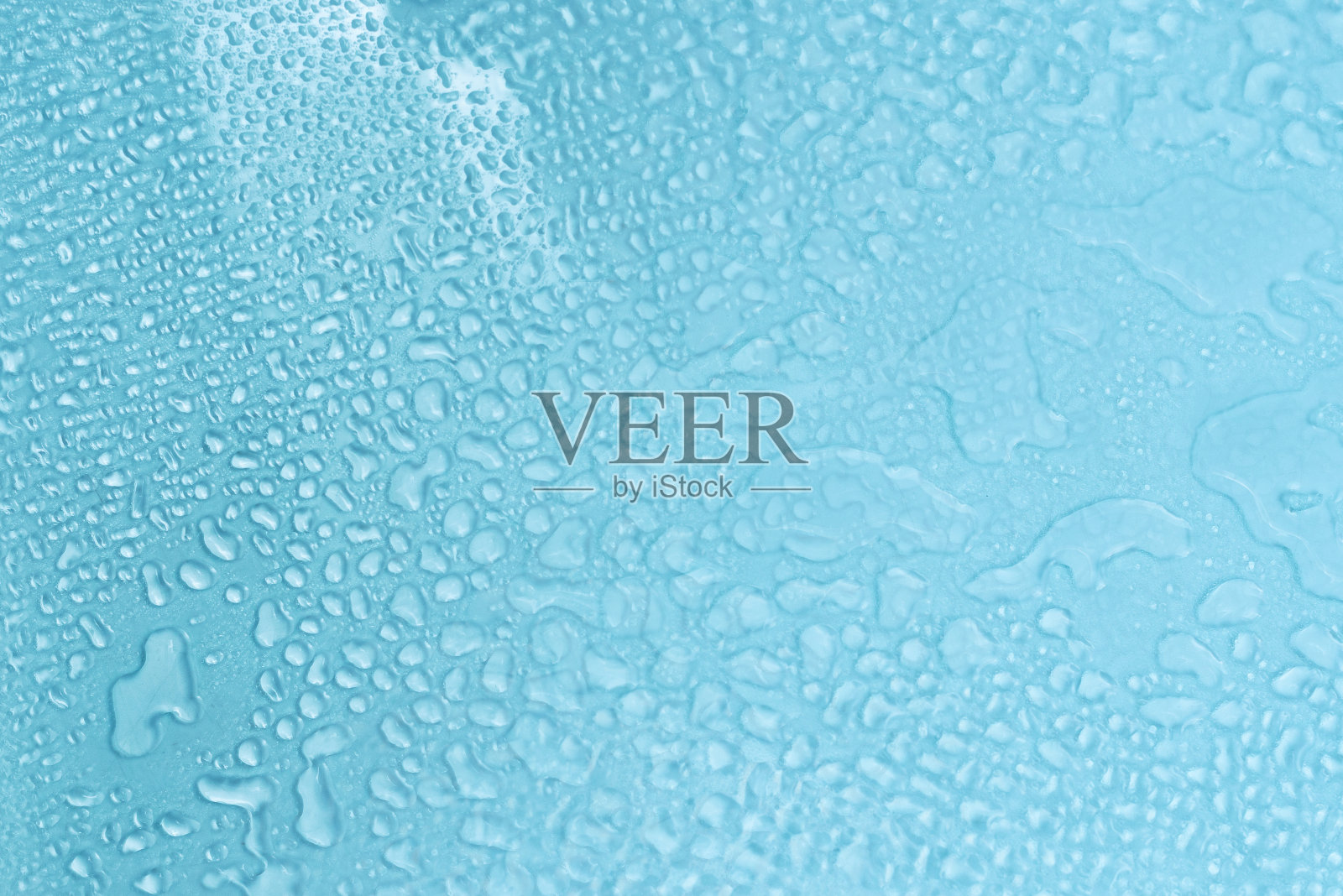 蓝色的玻璃上有水滴。湿的玻璃。照片摄影图片