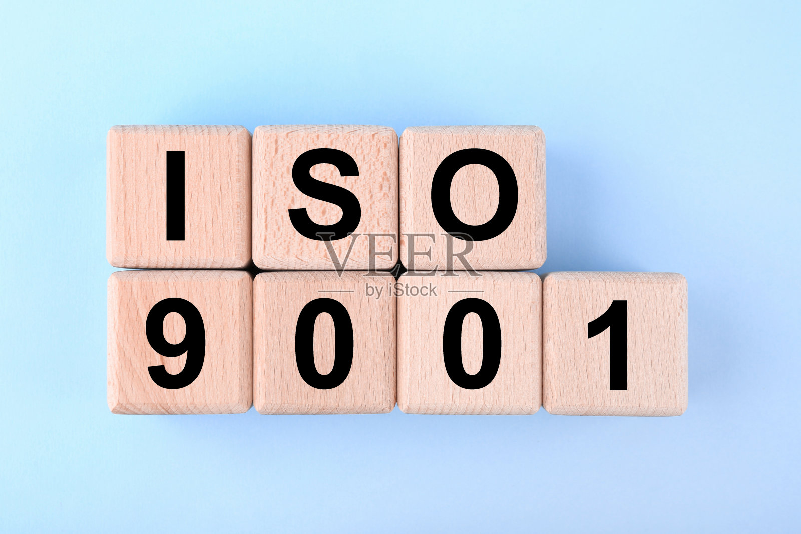 国际标准化组织。在浅蓝色的背景上，用缩写ISO和9001编号的木质立方体，平铺照片摄影图片