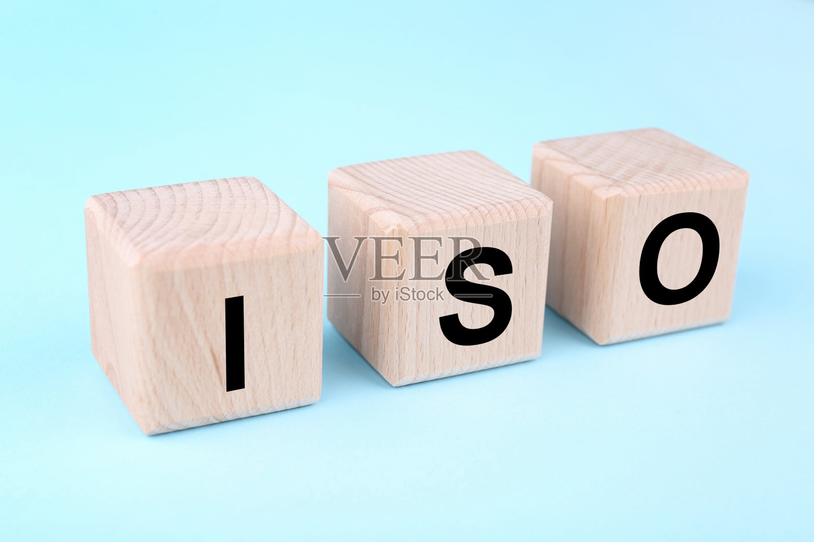国际标准化组织。浅蓝色背景上带有缩写ISO的木质立方体，特写照片摄影图片