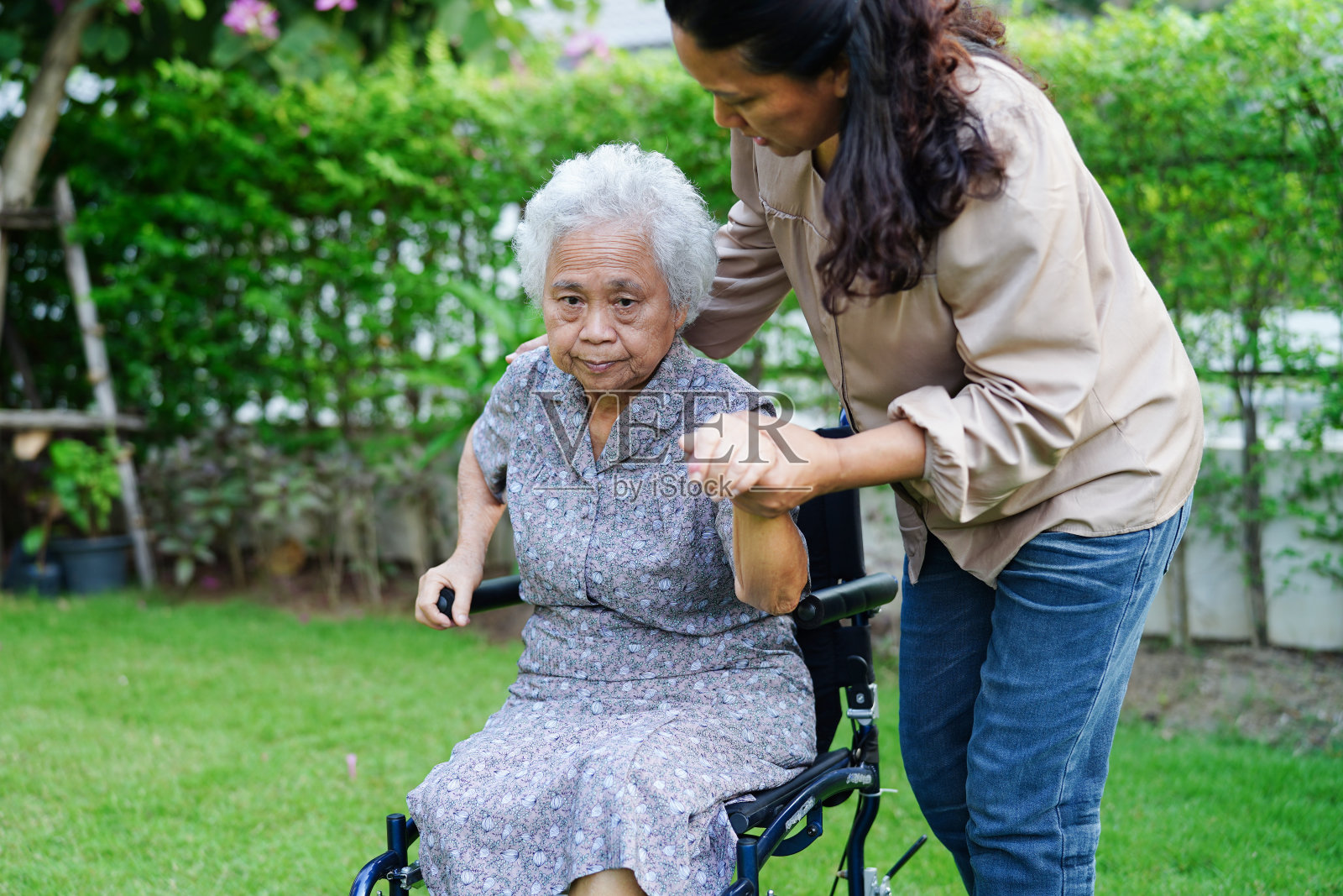 护理人员帮助坐在轮椅上的亚洲残疾老年妇女在公园，医疗概念。照片摄影图片