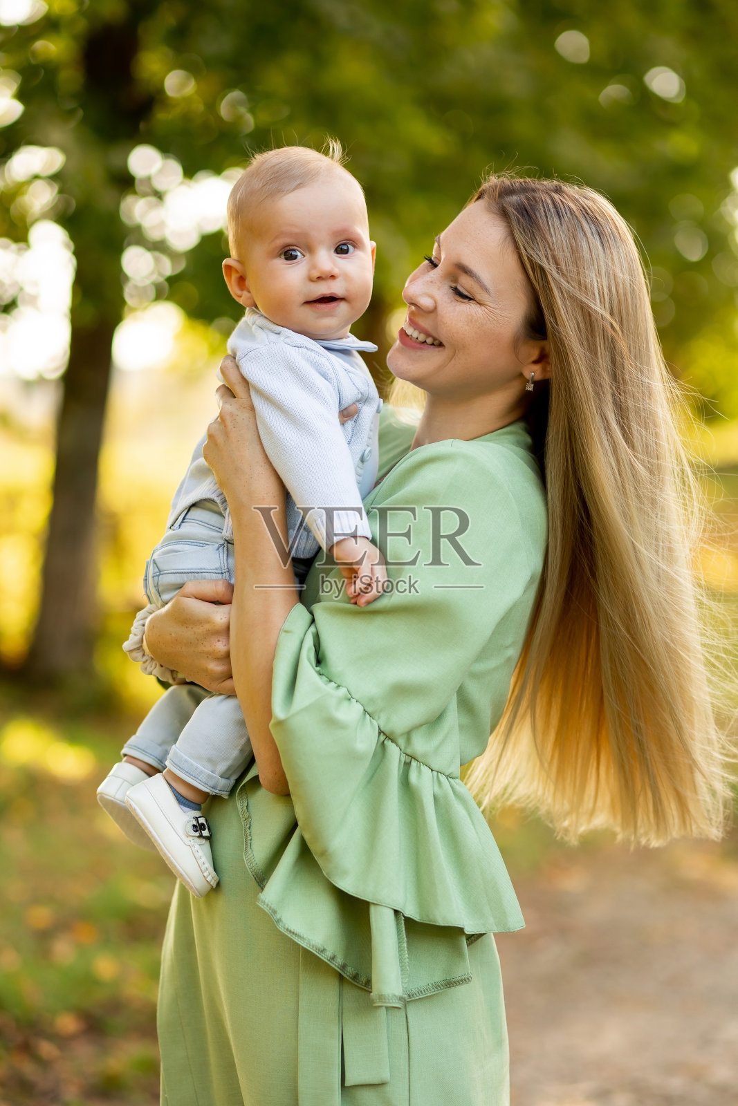 年轻美丽的母亲和她的孩子在户外玩耍。照片摄影图片