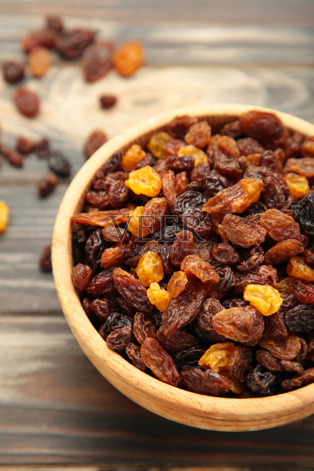 干葡萄干在棕色木制背景木碗。垂直图照片摄影图片