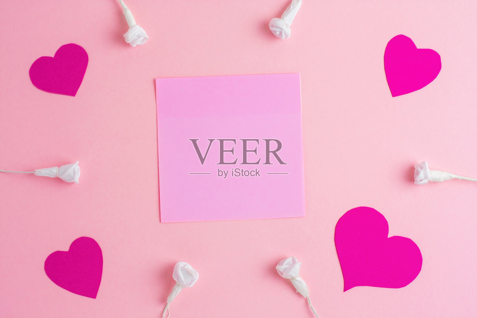 粉红色的便利贴，粉红色的心与白玫瑰在浅粉红色的背景。照片摄影图片