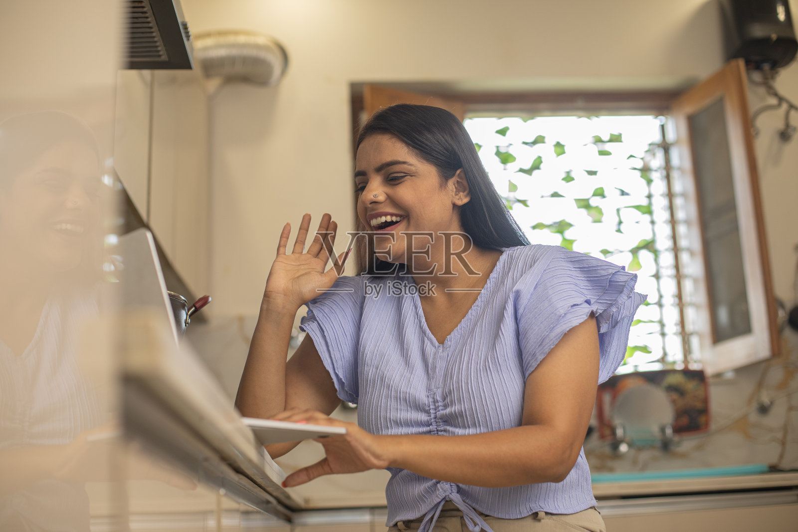 女人在厨房里用笔记本电脑做饭和工作照片摄影图片