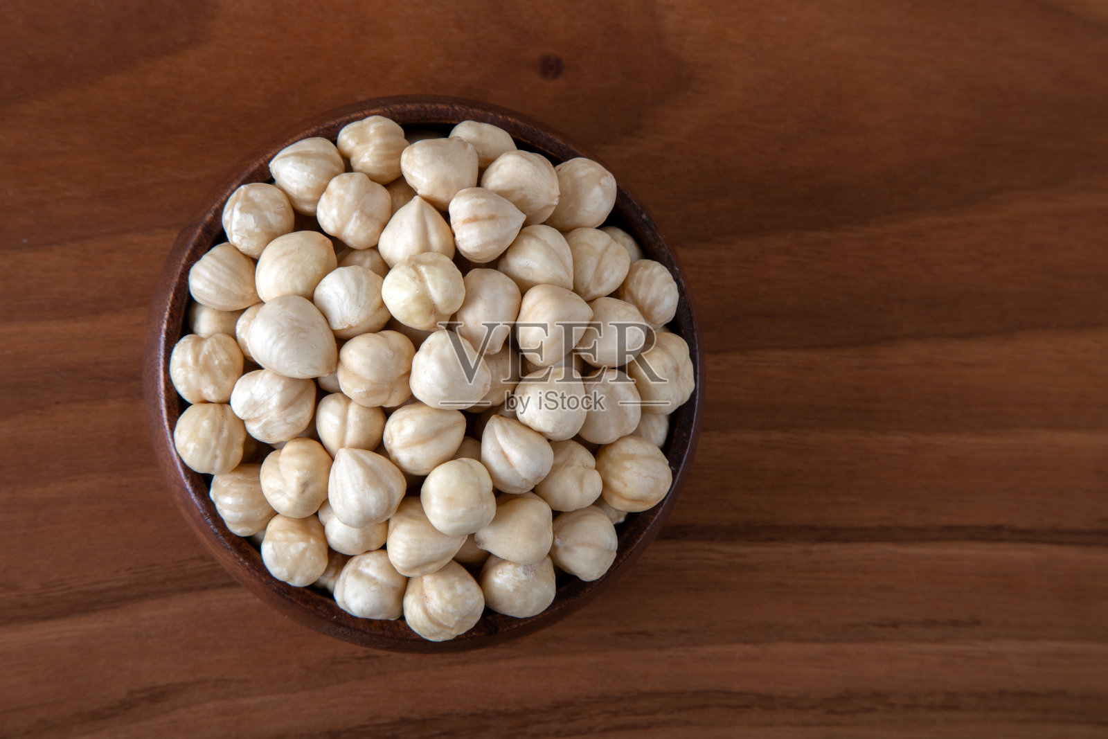 木桌上满满一碗榛子，俯视图照片摄影图片