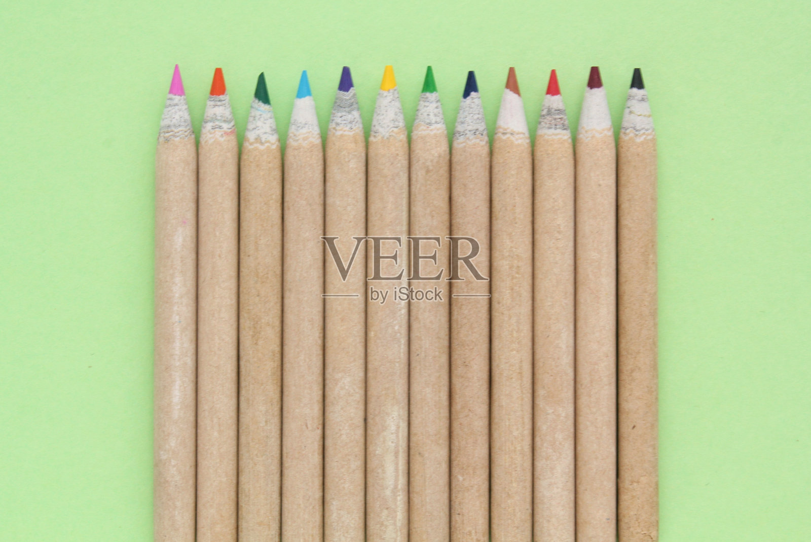 多色铅笔隔离在绿色背景。回到学校的概念。素描和绘画爱好。文具用品店。教育的过程。前视图。简约风格构图照片摄影图片