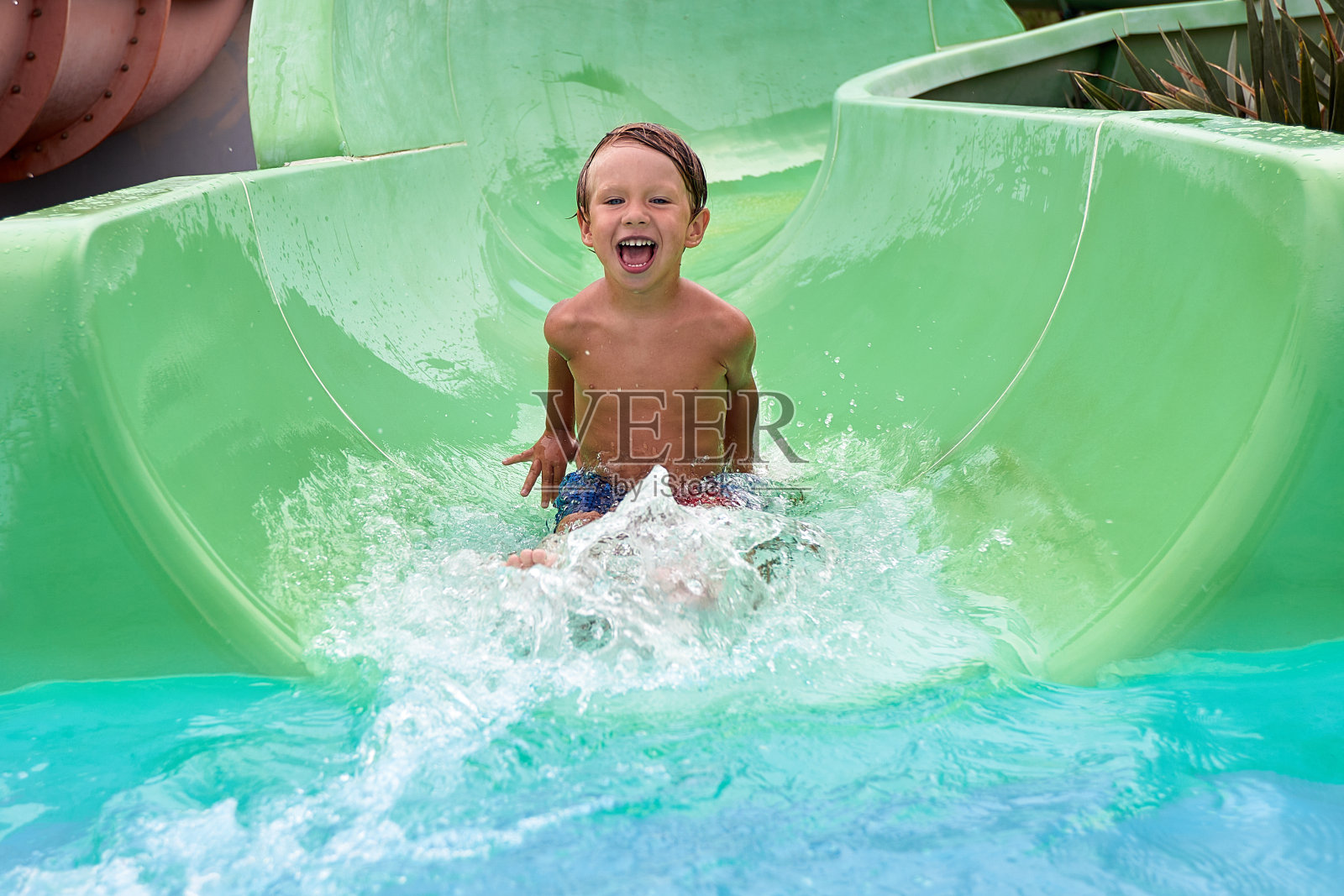 孩子们从水上乐园的夏季滑梯上下来，快乐的孩子们在游乐园，夏日的家庭度假。照片摄影图片