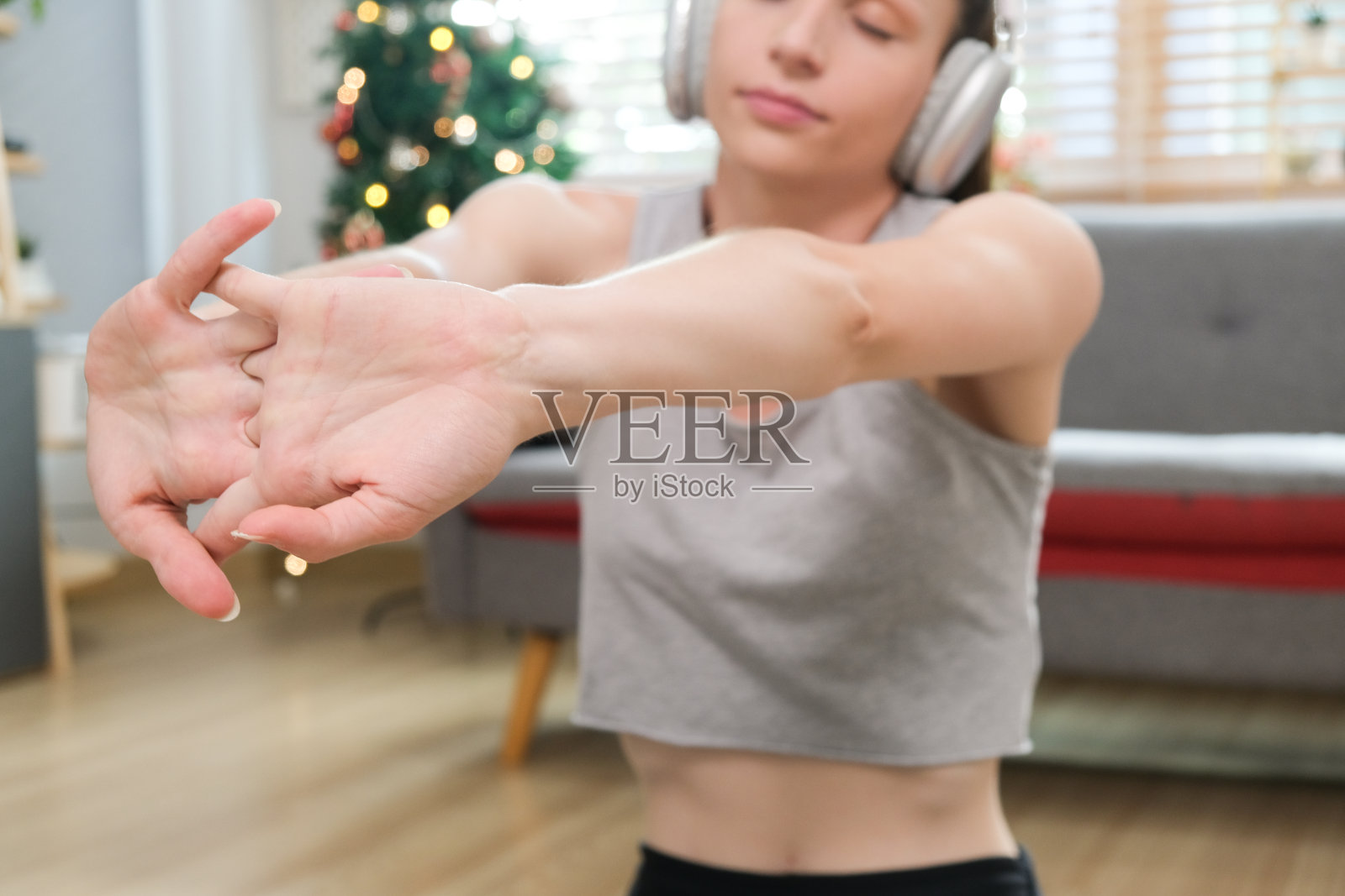 穿着运动服在家做瑜伽的快乐女人。穿着运动紧身裤和露脐上衣的年轻美女站在客厅的运动垫上，做着向前弓步运动照片摄影图片