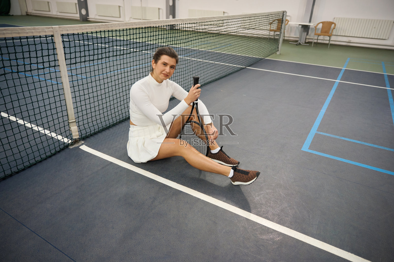 手持球拍的女子网球运动员坐在球场上看着镜头照片摄影图片