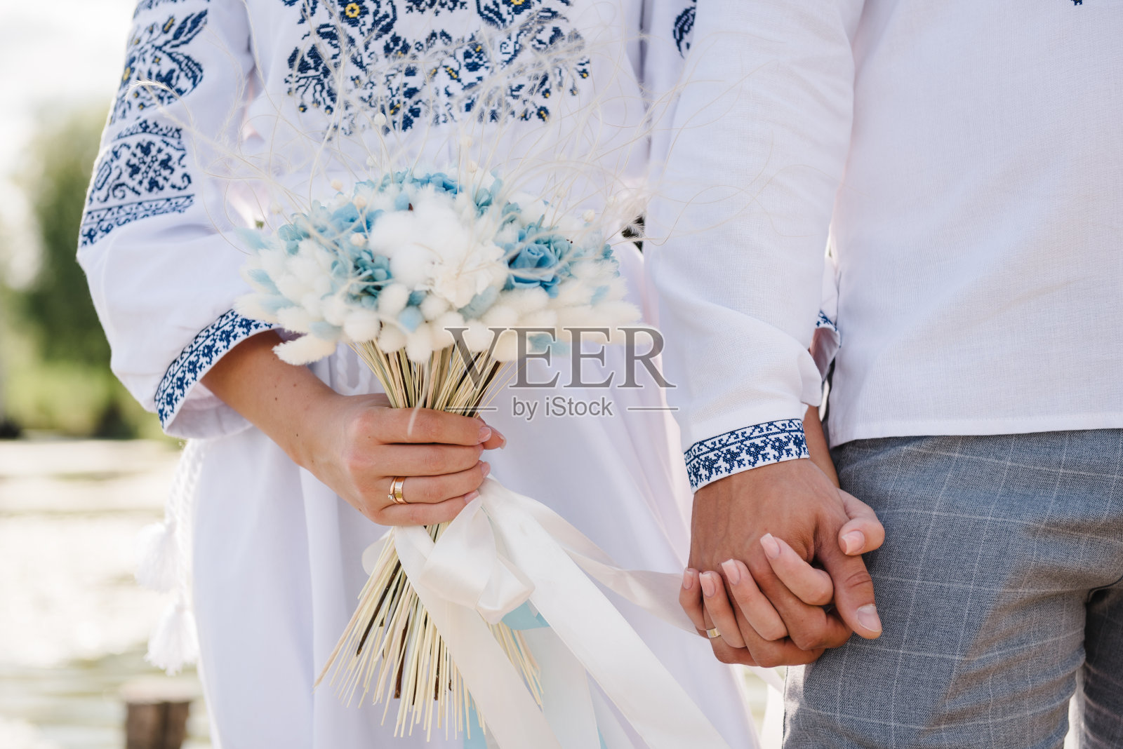 身着乌克兰传统服装的夫妇手牵着手。穿着民族服装的民族婚礼仪式。传统。新娘和新郎在户外穿着刺绣的礼服和衬衫。照片摄影图片