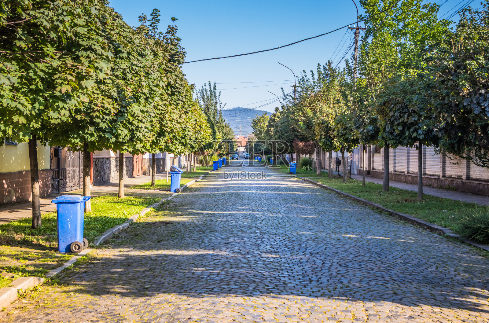 在一个小镇的街道上，每个房子附近都有蓝色的垃圾桶。在一个舒适的欧洲小城市集中收集垃圾。在一周的某一天收集垃圾。照片摄影图片
