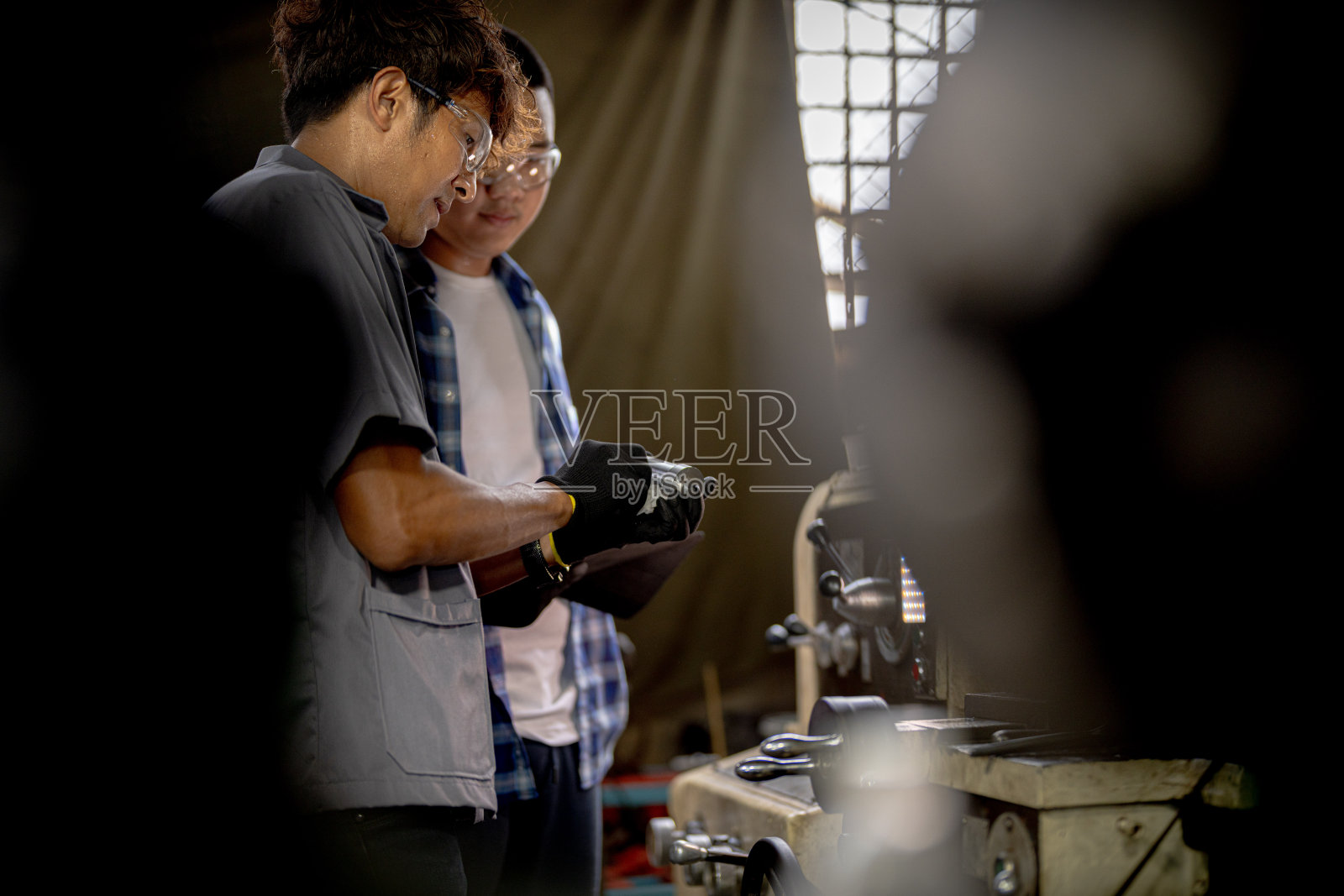 工人们正在检查机器安装用的钢件。一队师生正在钢铁厂学习使用重型机械。工人们在进行产品质量控制时相互配合。照片摄影图片