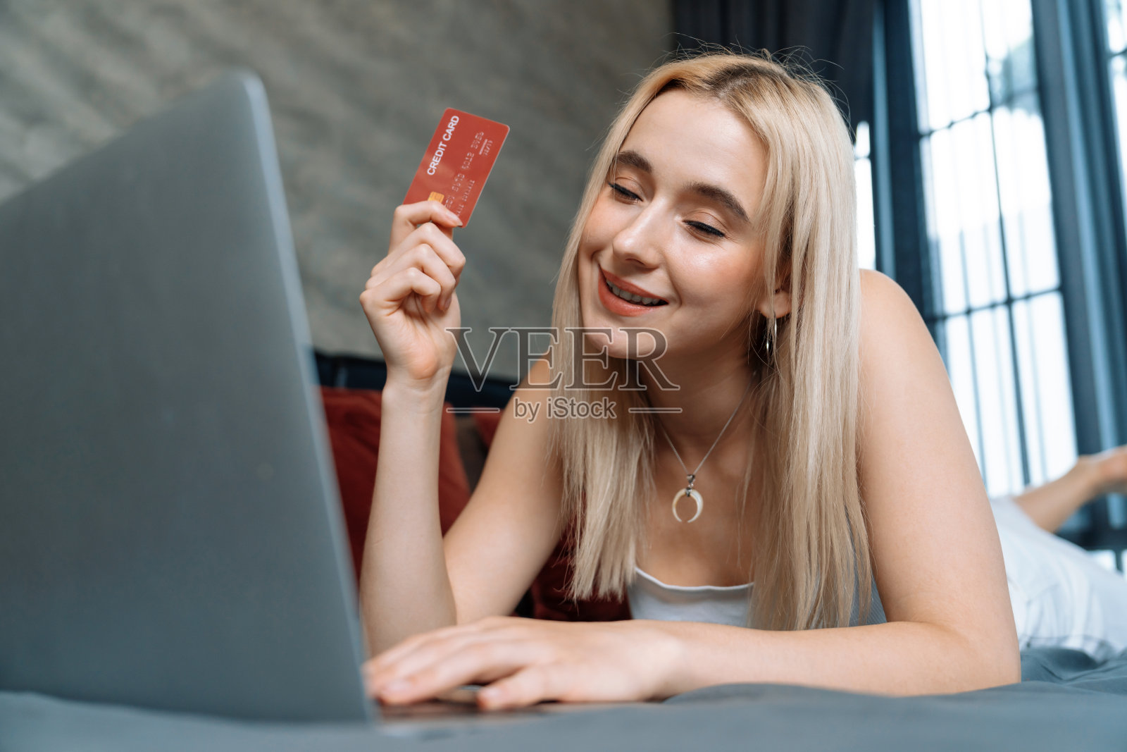 年轻女子用笔记本电脑和信用卡进行网上银行。快乐无忧的照片摄影图片