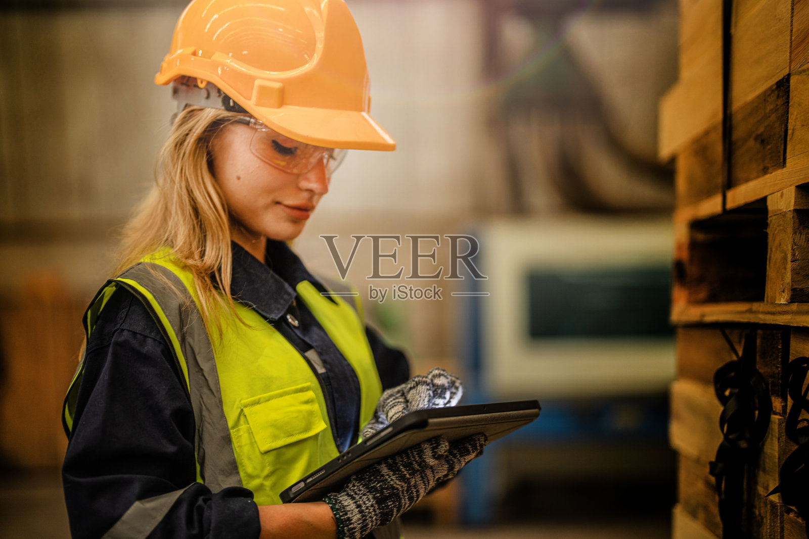 穿着安全制服，头戴安全帽的女工木匠，在车间生产中检查木制品的质量。男女工人在黑暗的仓库工业木材。照片摄影图片