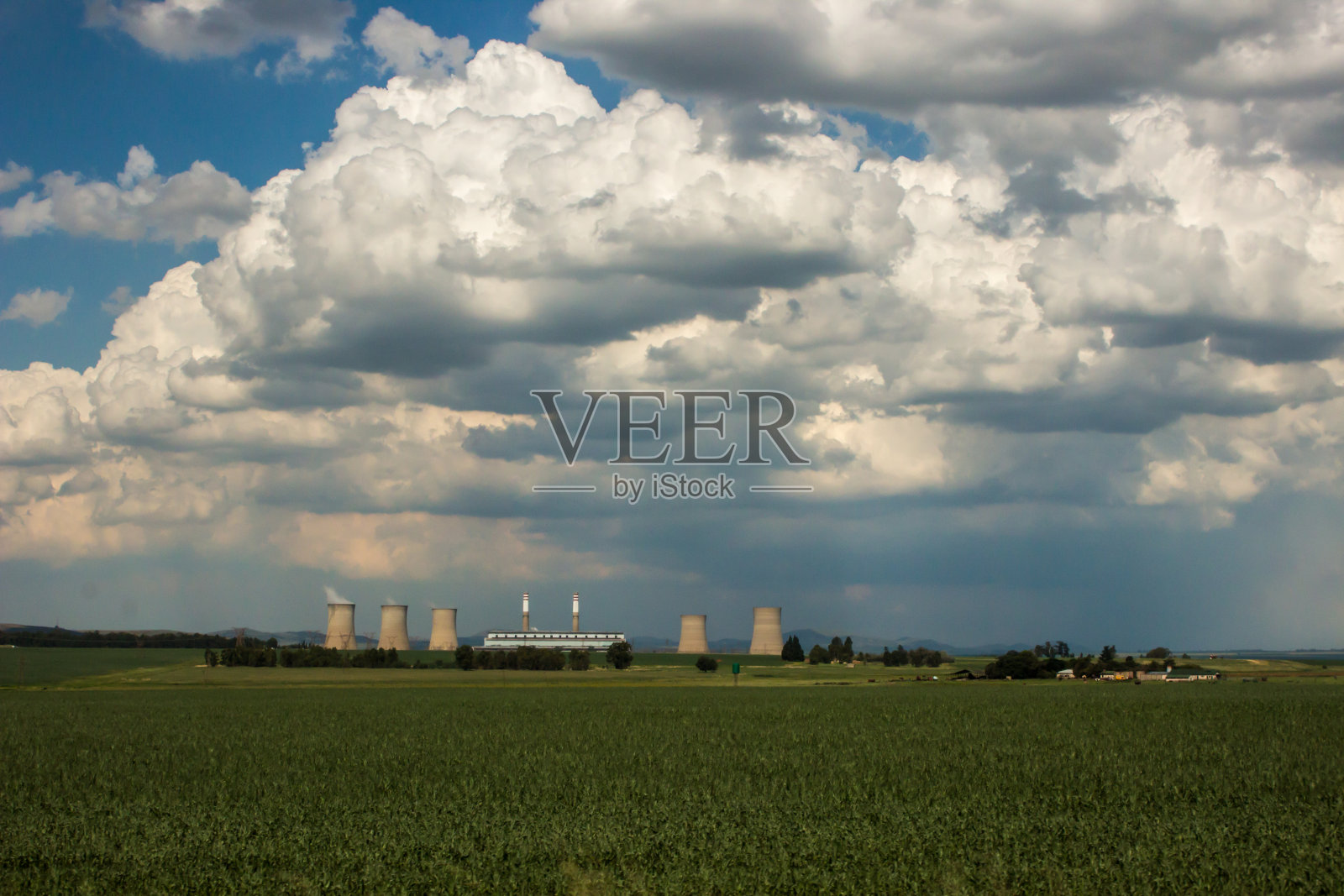 积云聚集在南非田野间的燃煤发电站上空。照片摄影图片