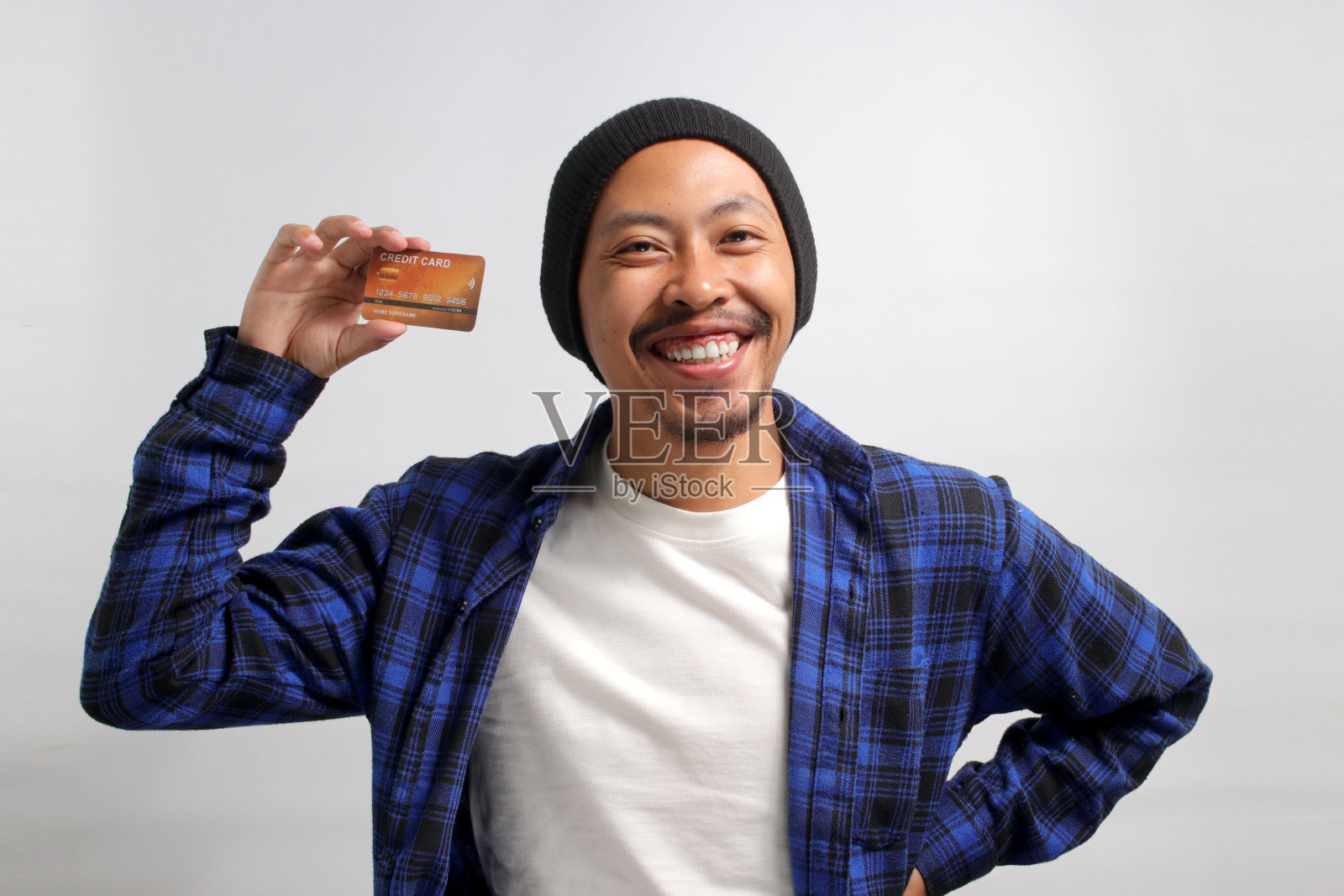 一名亚洲男子手里拿着一张信用卡，孤立在白色背景上照片摄影图片