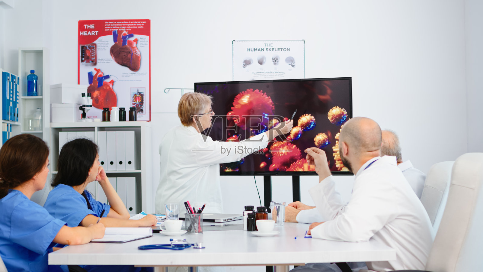 高级医生指着医院办公室的监视器解释病毒的发展照片摄影图片