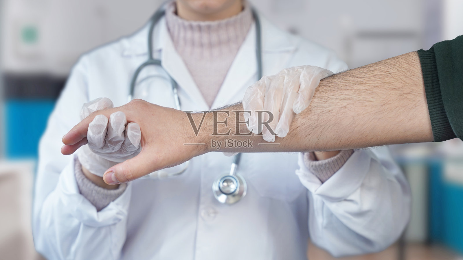 年轻的骨科医生抱着病人的右臂照片摄影图片