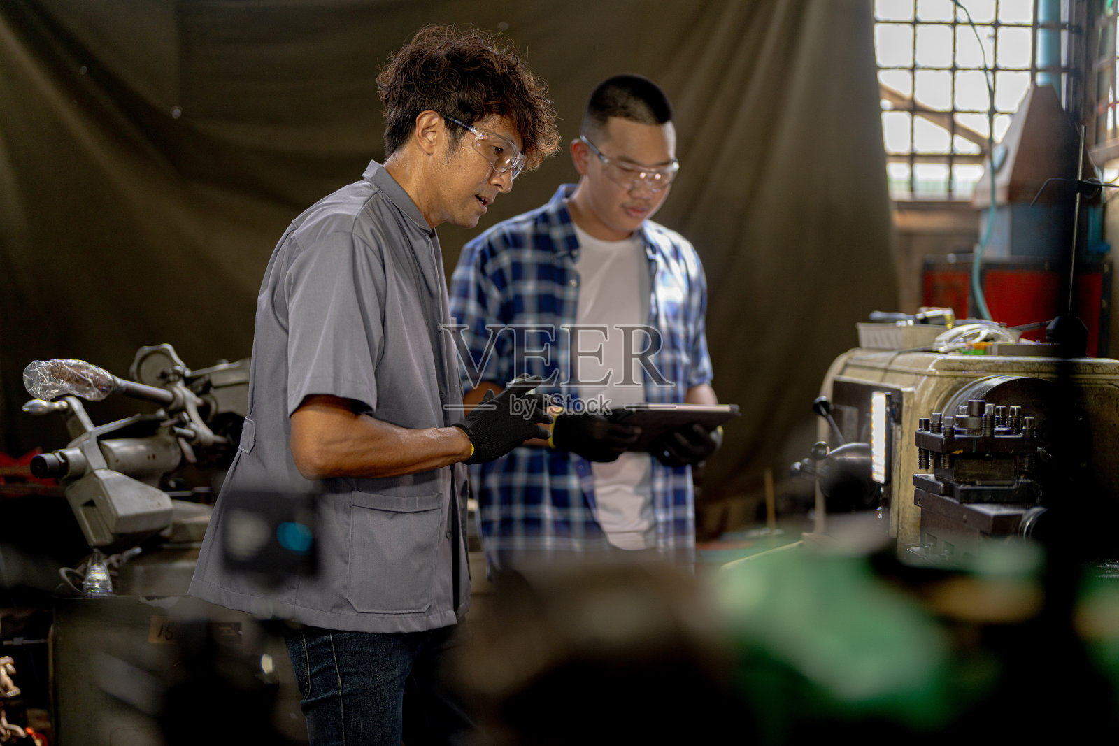 工人们正在检查机器安装用的钢件。一队师生正在钢铁厂学习使用重型机械。工人们在进行产品质量控制时相互配合。照片摄影图片