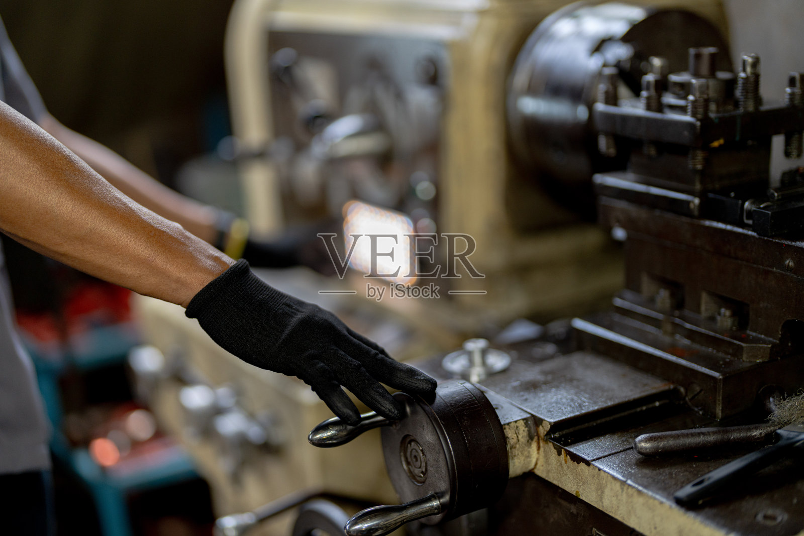 金属车床的近距离手动操作。轧钢机轧钢柱。金属加工行业。工人用手检查机械发动机。在工厂维修金属机器钻头的技术员照片摄影图片