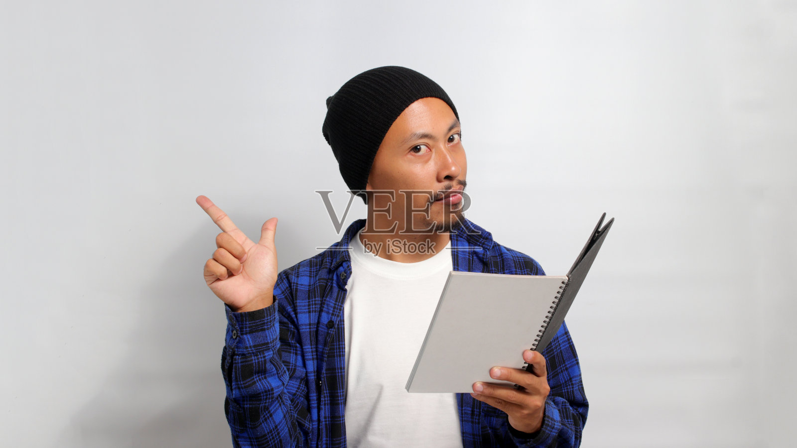 一名年轻的亚洲学生兴奋地对着镜头微笑，指着旁边的空白复印区照片摄影图片