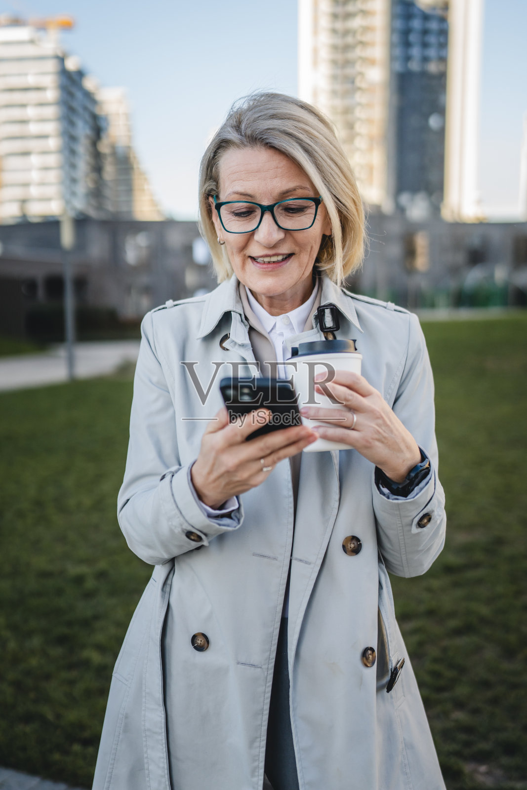 女人站在大楼前拿着咖啡去用手机照片摄影图片