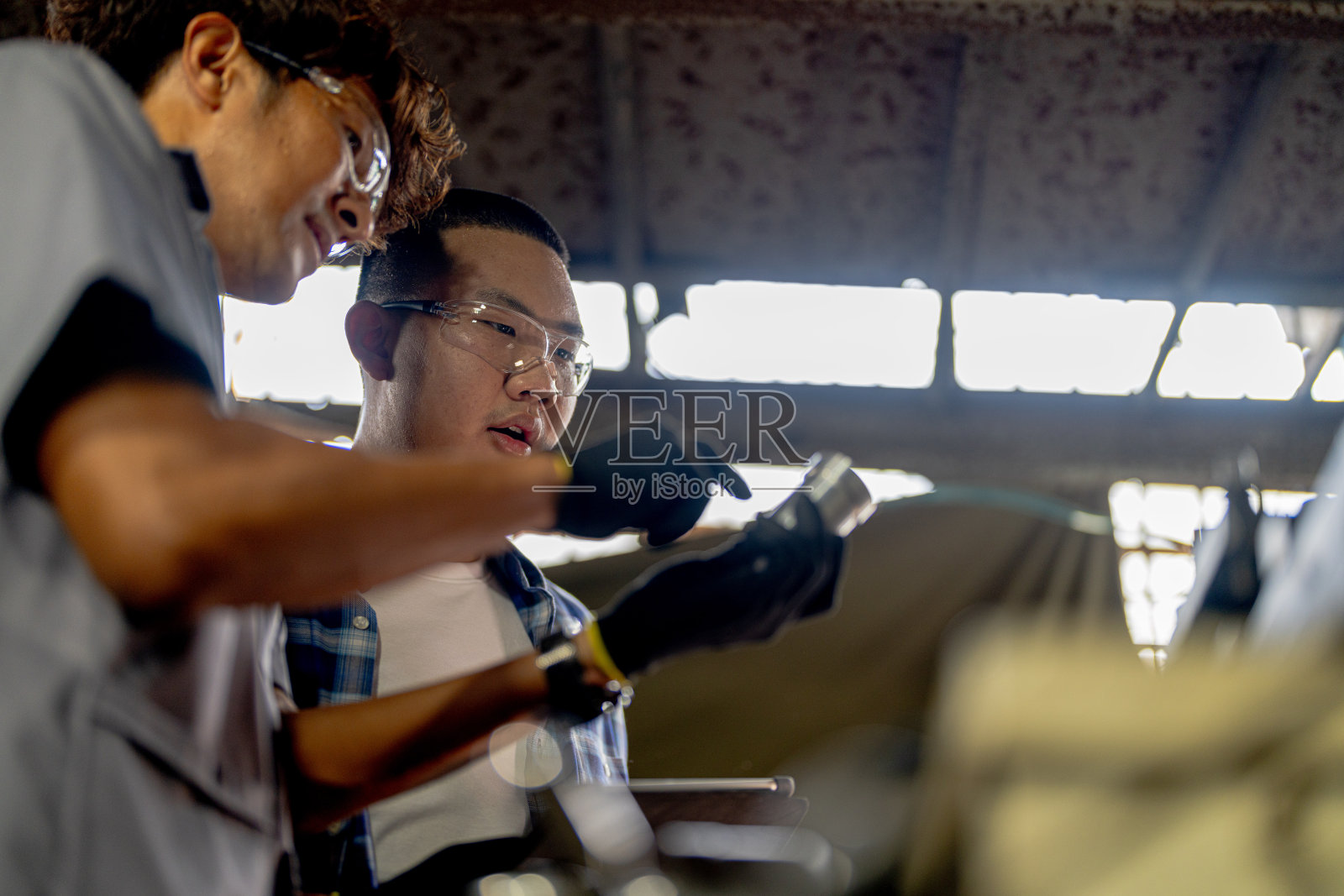 工人们正在检查机器安装用的钢件。一队师生正在钢铁厂学习使用重型机械。工人们在进行产品质量控制时相互配合。照片摄影图片