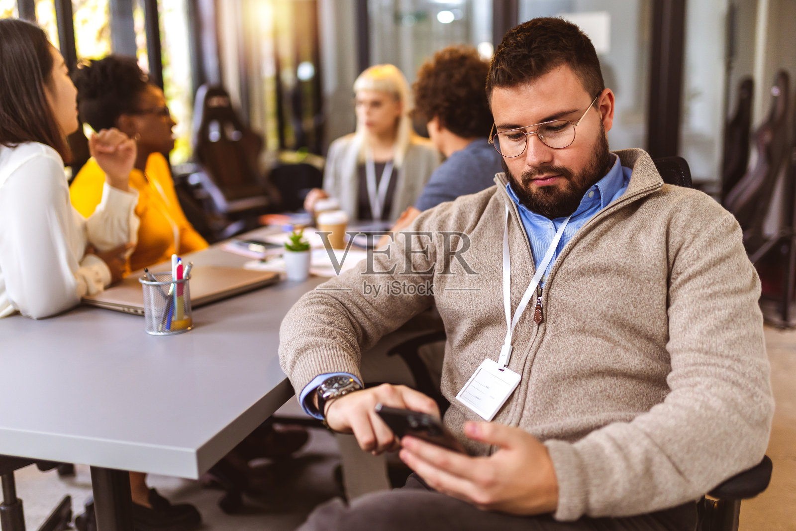 一名员工在办公室使用电话，而他的同事在后台使用。照片摄影图片