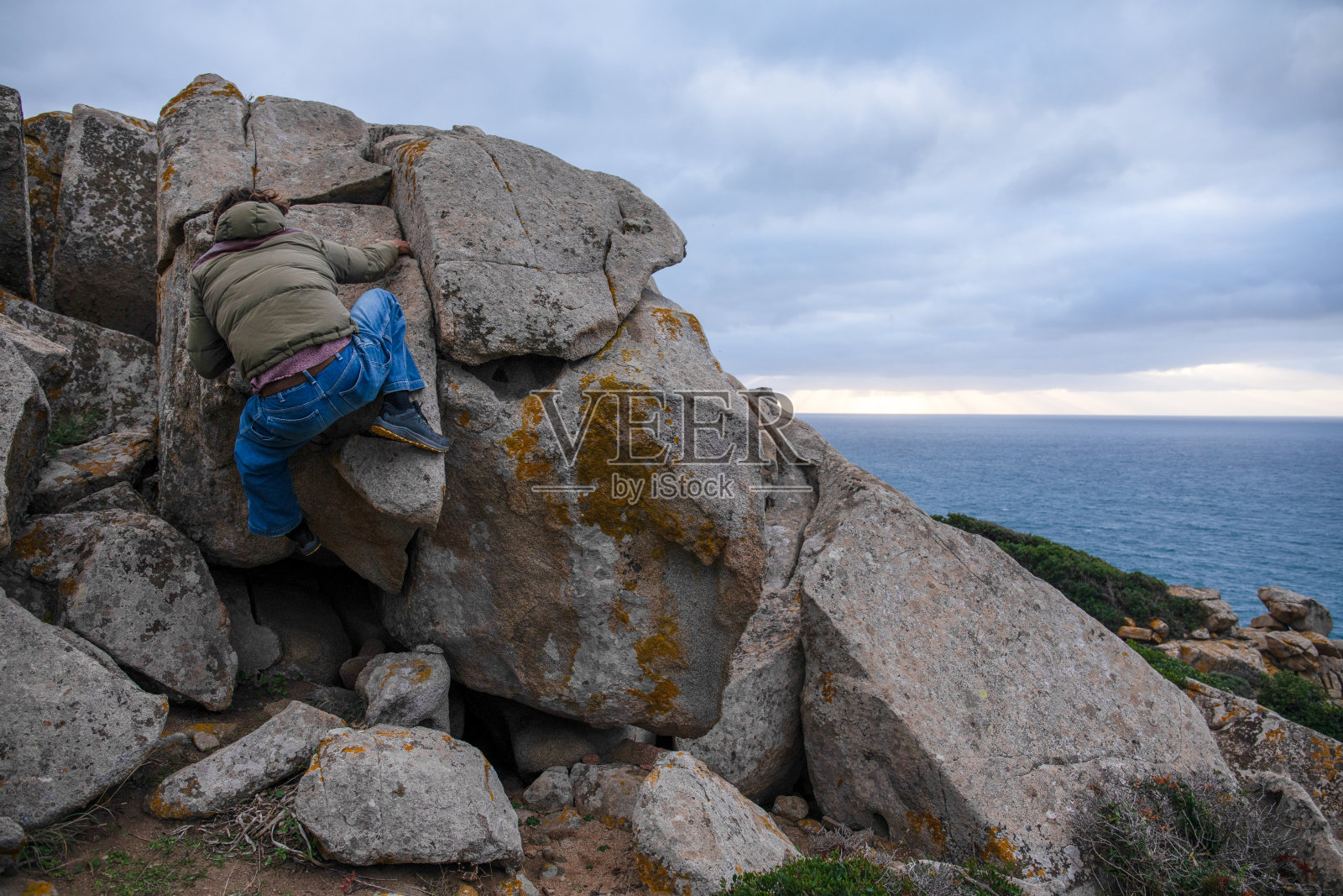 年轻人爬上巨石照片摄影图片