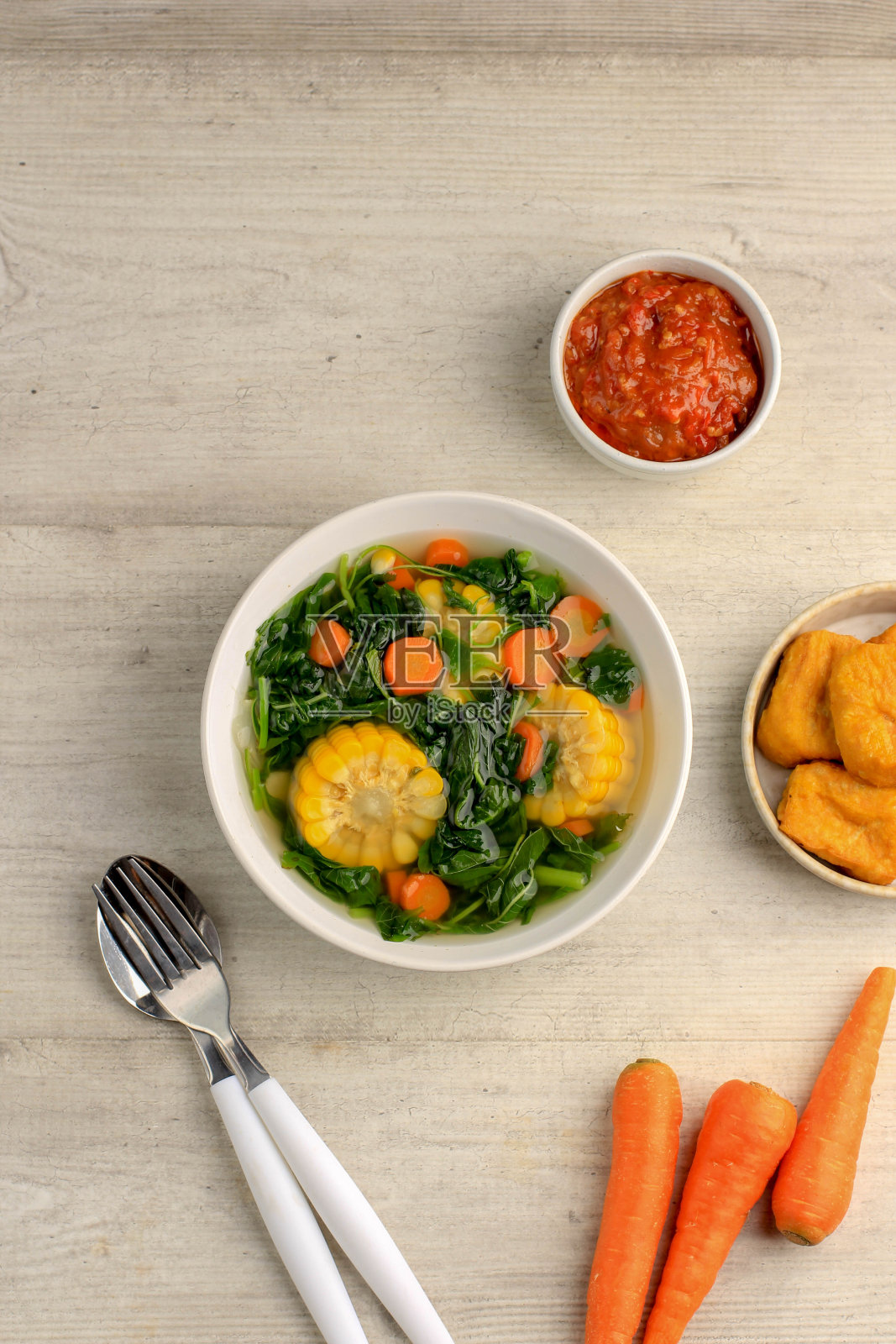 Sayur Bening Bayam是印尼家庭的每日菜单，由菠菜，胡萝卜和玉米制成。用大蒜和盐调味。配豆腐、炒咸鱼、参巴等各种配菜。照片摄影图片