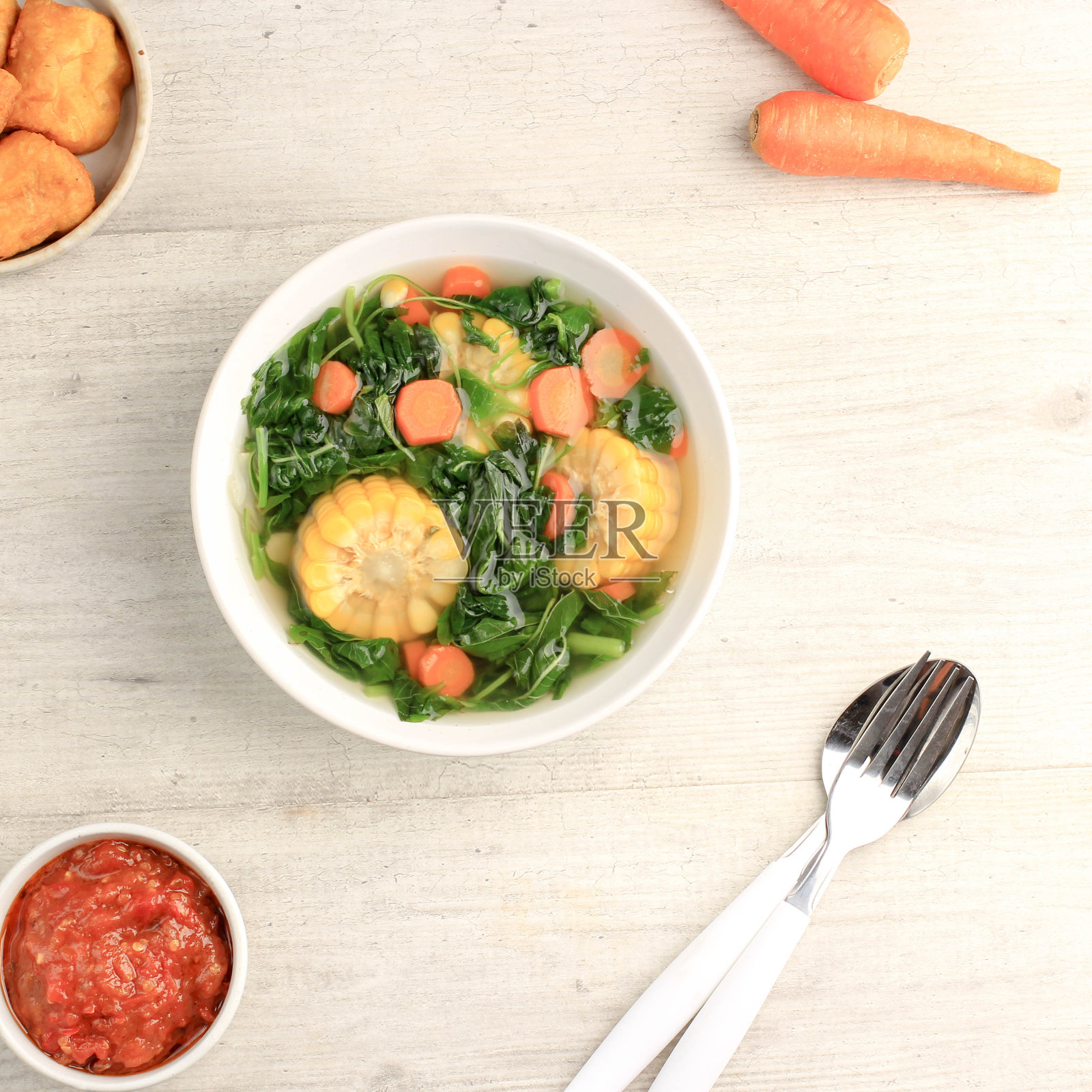 Sayur Bening Bayam是印尼家庭的每日菜单，由菠菜，胡萝卜和玉米制成。用大蒜和盐调味。配豆腐、炒咸鱼、参巴等各种配菜。照片摄影图片