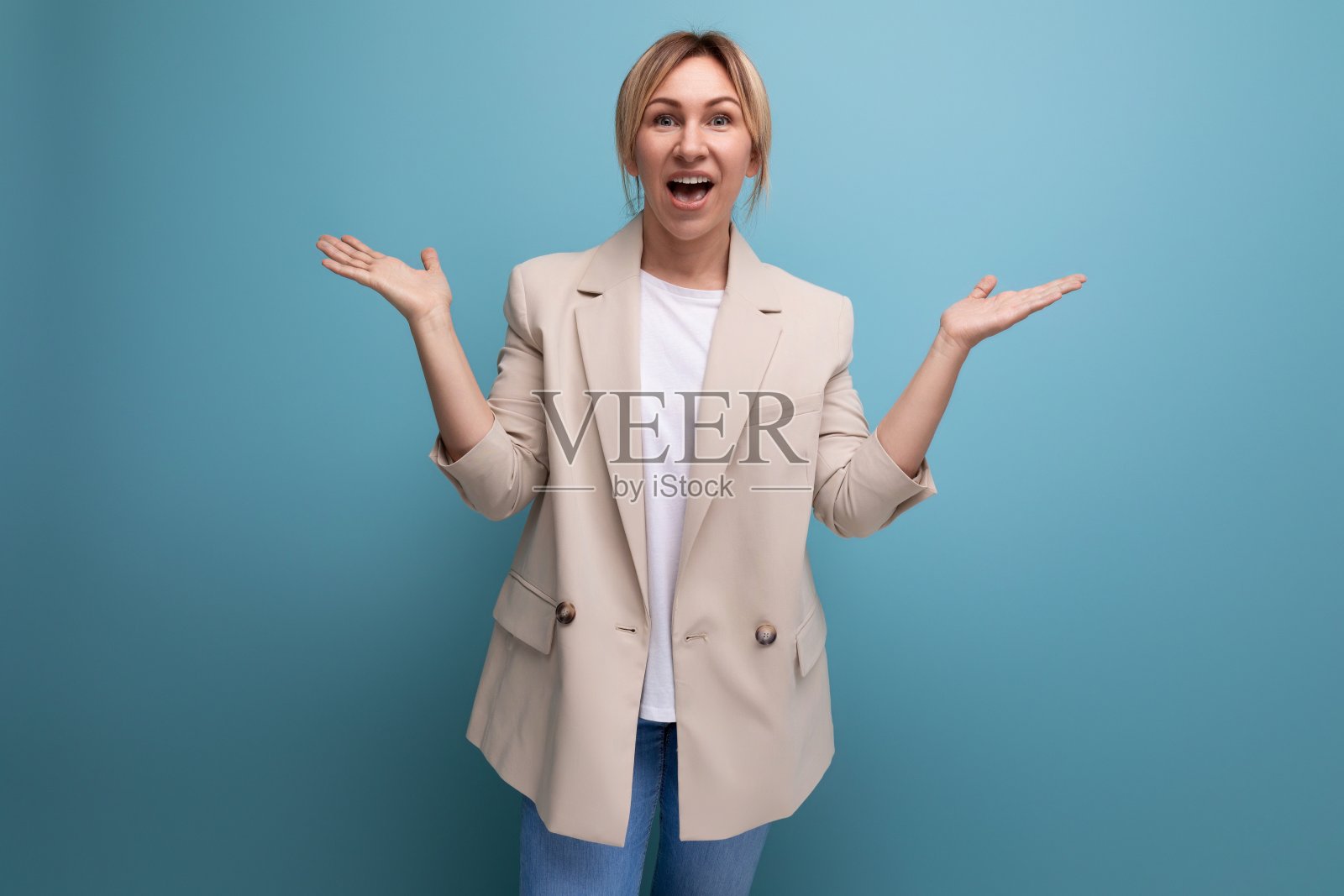 开朗、微笑、自信、金发碧眼的年轻人，穿着夹克，背景是一间有复印空间的工作室照片摄影图片