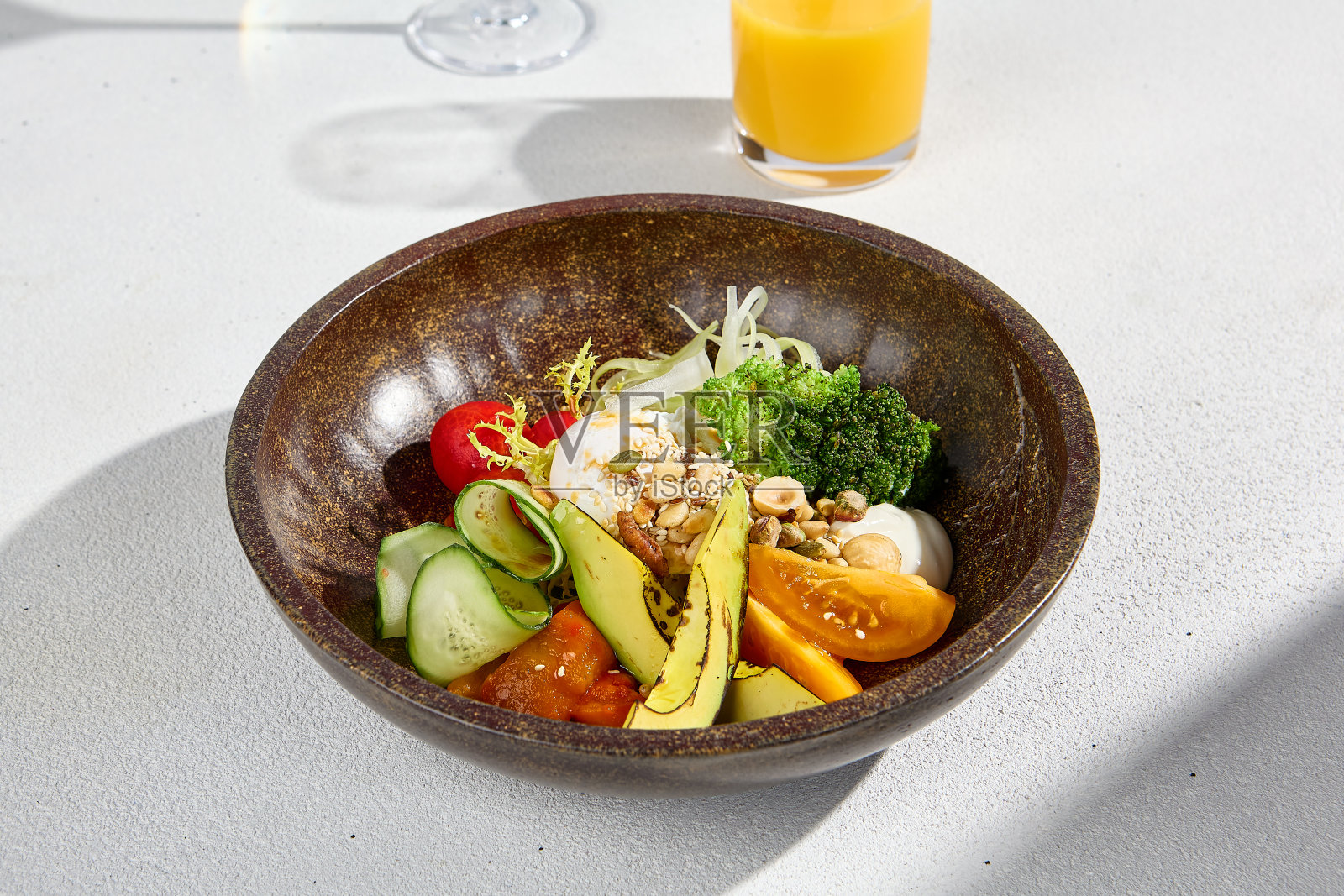 沙拉碗，牛油果，蔬菜，水煮蛋，橙汁和起泡酒在强烈的阳光下照片摄影图片