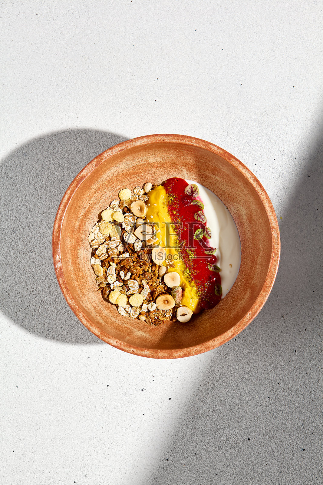 俯视图自制酸奶与格兰诺拉麦片，浆果慕斯，芒果在一个陶土碗照片摄影图片