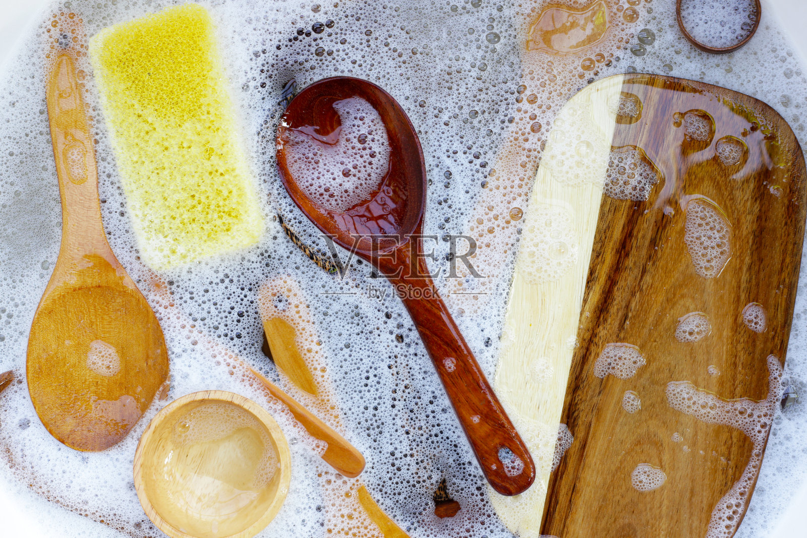 木制厨具浸在水中，还有洗碗液的气泡照片摄影图片