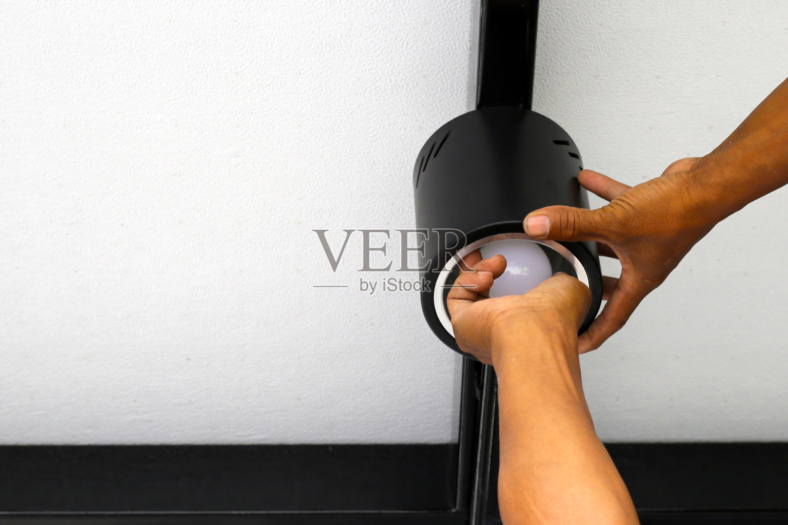 电工在天花板上安装灯的手。照片摄影图片