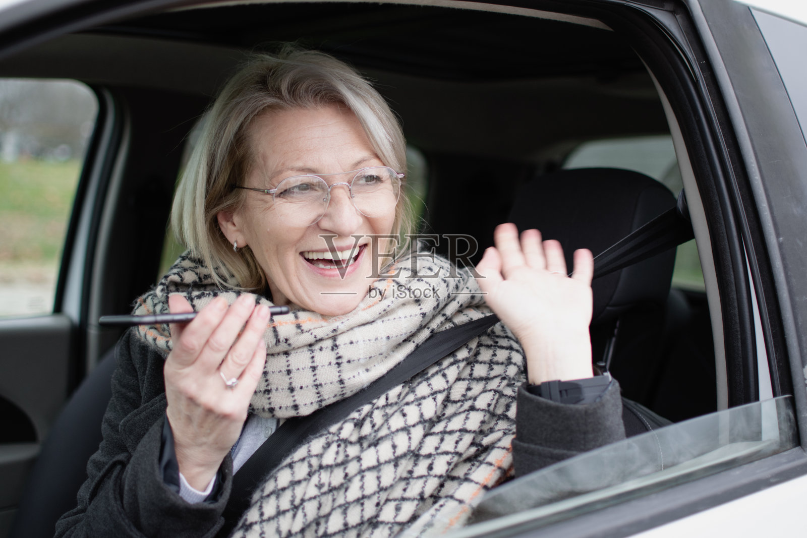 成熟的金发女人坐在车里玩手机照片摄影图片